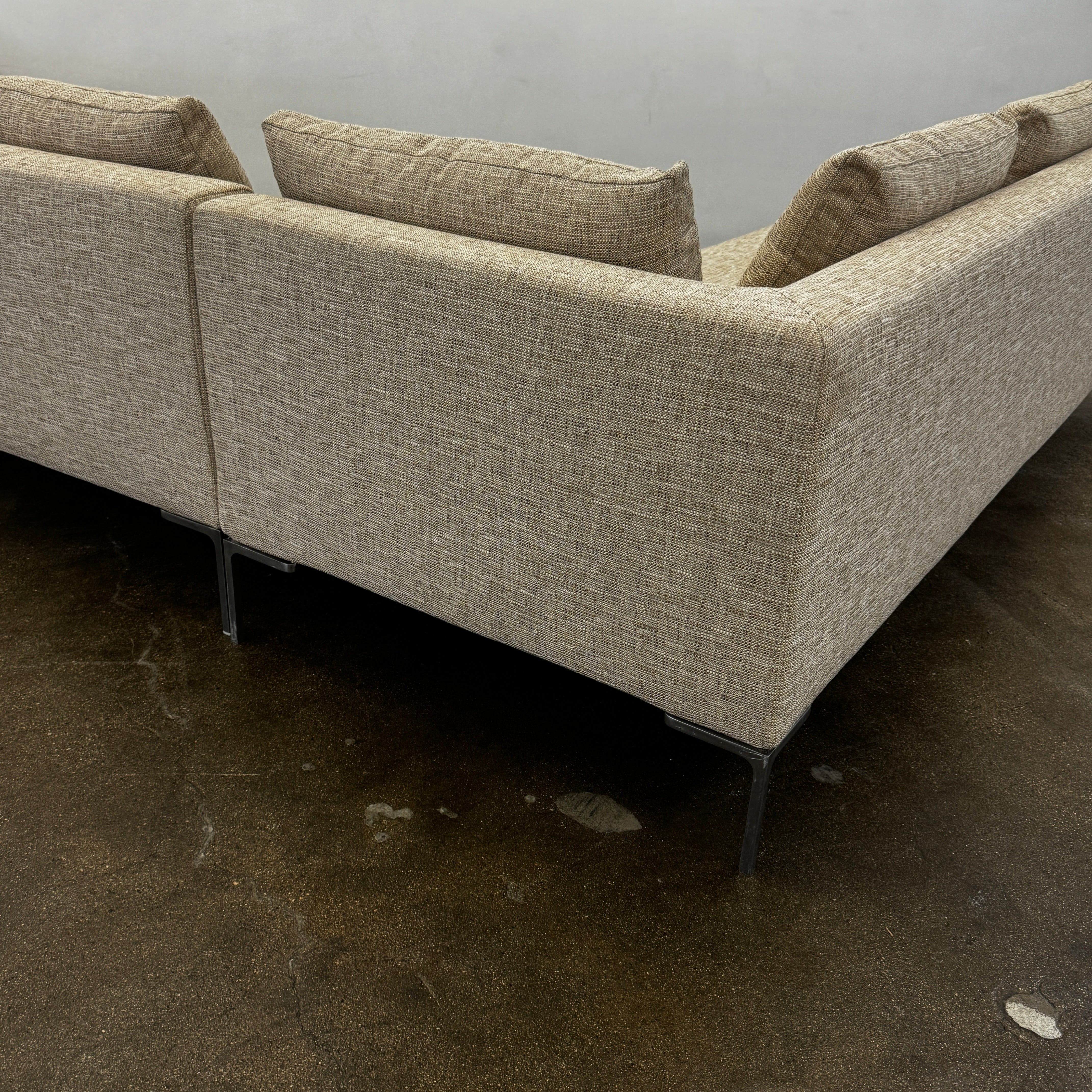 A beige B&B Italia Charles Sectional with five back cushions and metal legs sits on a concrete floor against a plain white wall.