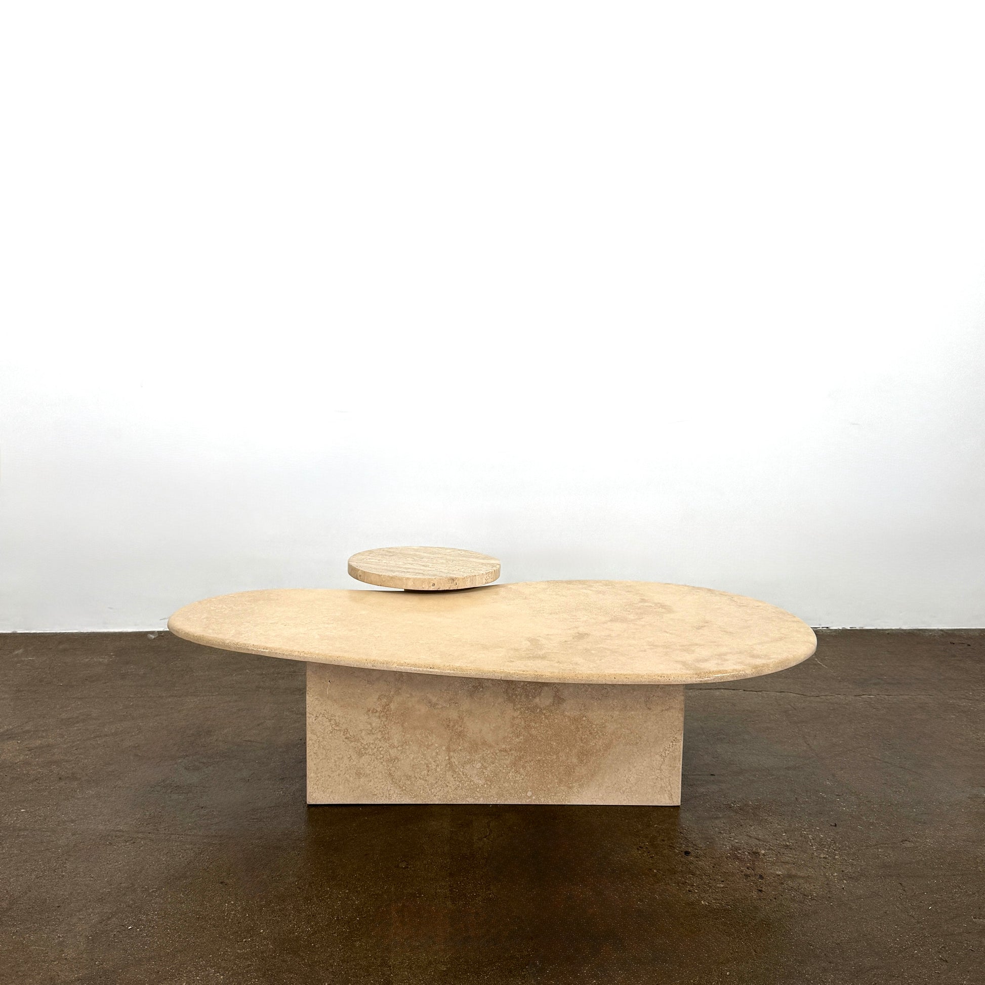 The Custom Travertine Coffee Table Set by Custom features two beige stone surfaces—one oval, one round—supported by solid travertine legs, offering sculptural elegance and modern style to any space.