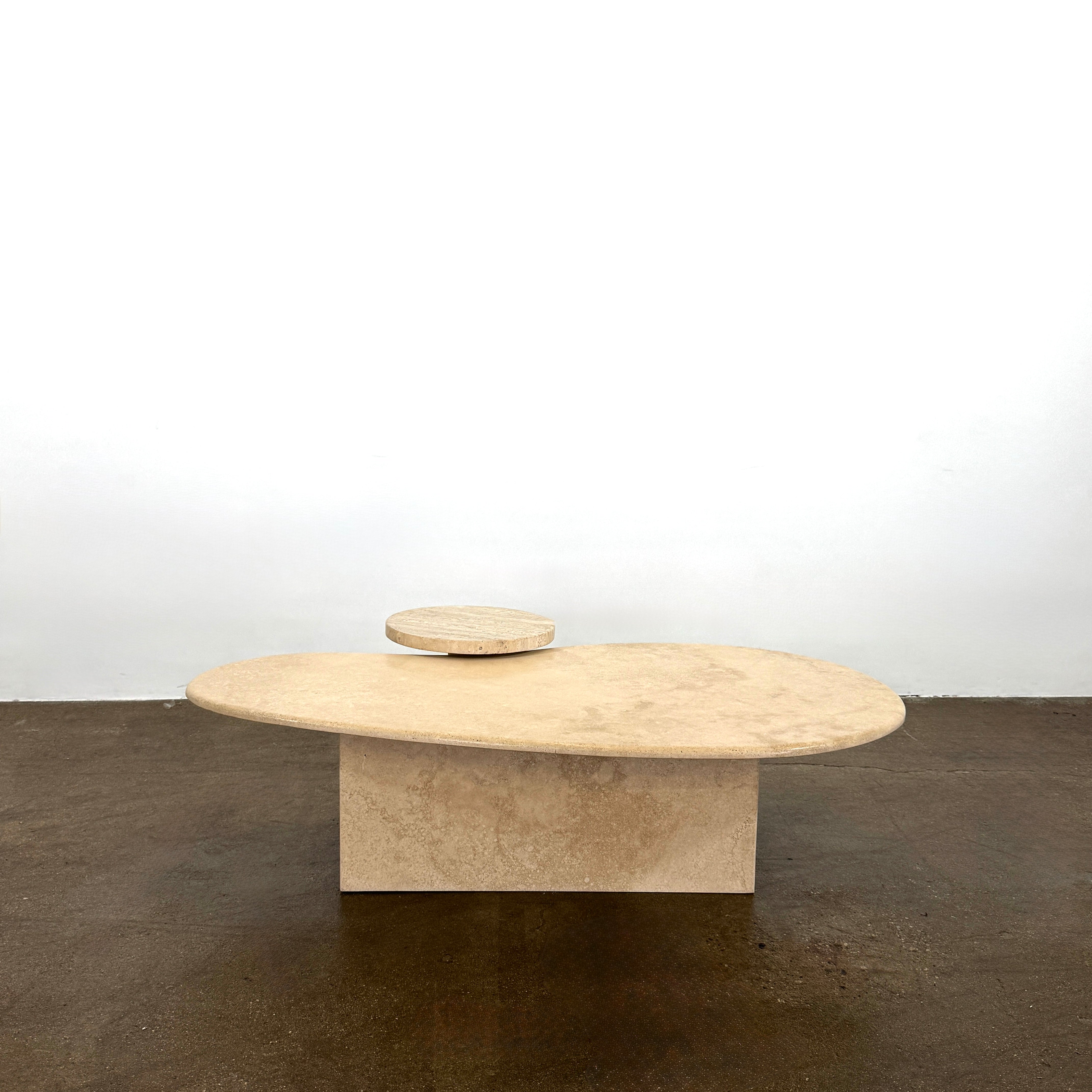 The Custom Travertine Coffee Table Set by Custom features two beige stone surfaces—one oval, one round—supported by solid travertine legs, offering sculptural elegance and modern style to any space.