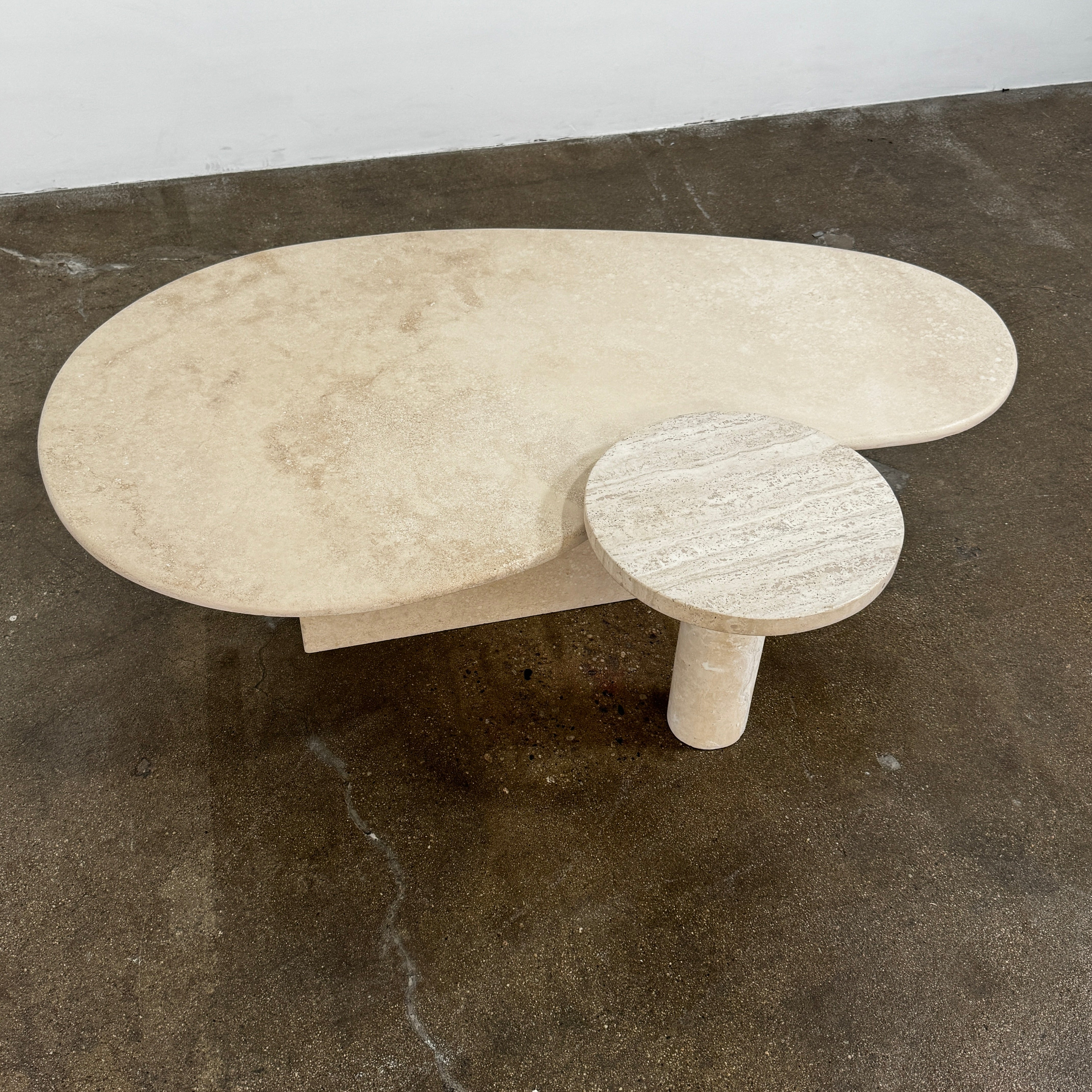 The Custom Travertine Coffee Table Set by Custom features two beige stone surfaces—one oval, one round—supported by solid travertine legs, offering sculptural elegance and modern style to any space.