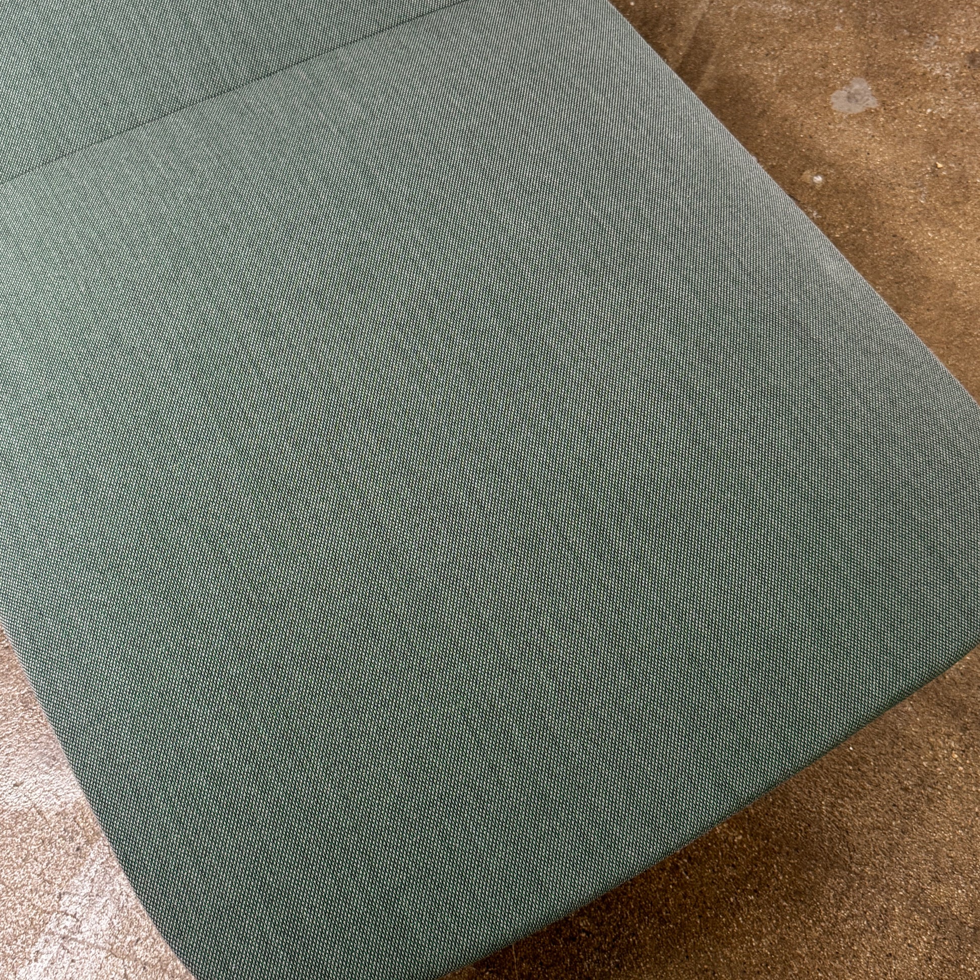The Muuto Oslo 2-seat sofa & bench by Muuto, featuring modern green upholstery and slim black legs inspired by Danish design, stands in a bright room with beige walls and sheer white curtains.