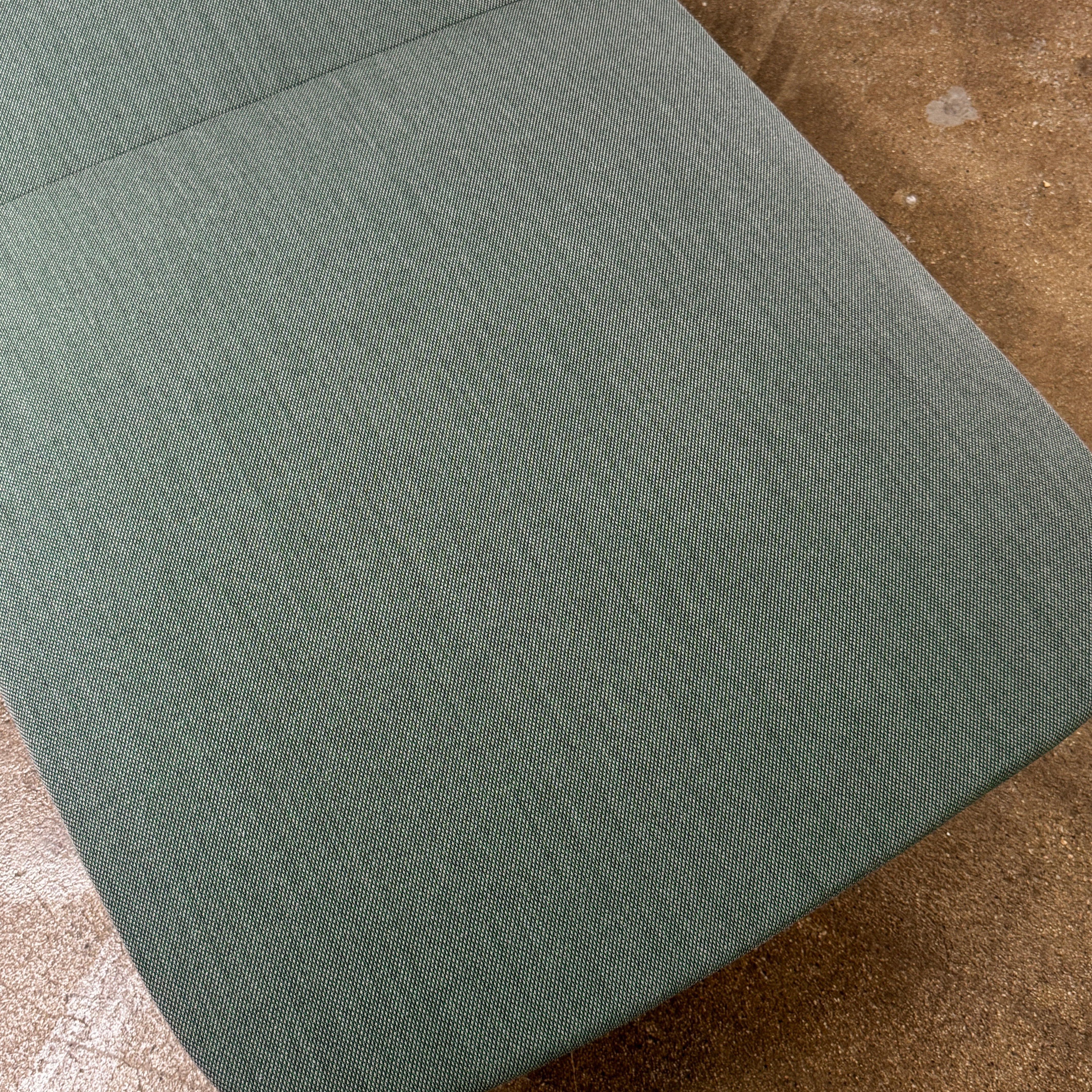 The Muuto Oslo 2-seat sofa & bench by Muuto, featuring modern green upholstery and slim black legs inspired by Danish design, stands in a bright room with beige walls and sheer white curtains.