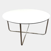 The Minotti Louis Round Dining Table features a white top and a modern metal base with three intersecting legs, reflecting Minotti’s signature style.