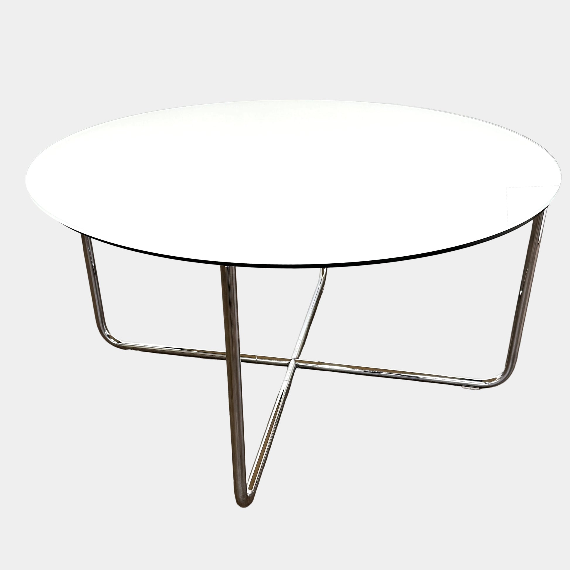 The Minotti Louis Round Dining Table features a white top and a modern metal base with three intersecting legs, reflecting Minotti’s signature style.