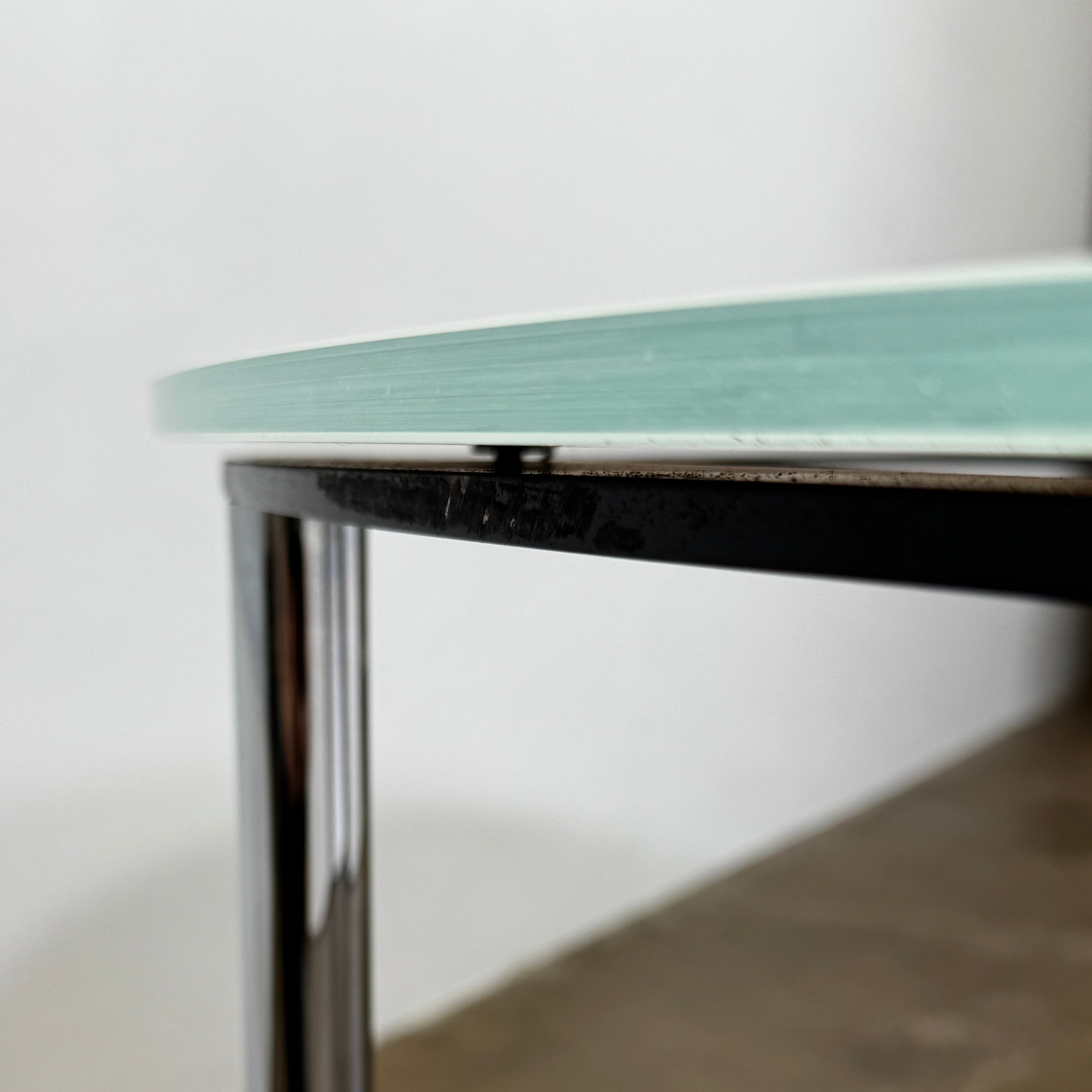 The Minotti Louis Round Dining Table features a white top and a modern metal base with three intersecting legs, reflecting Minotti’s signature style.