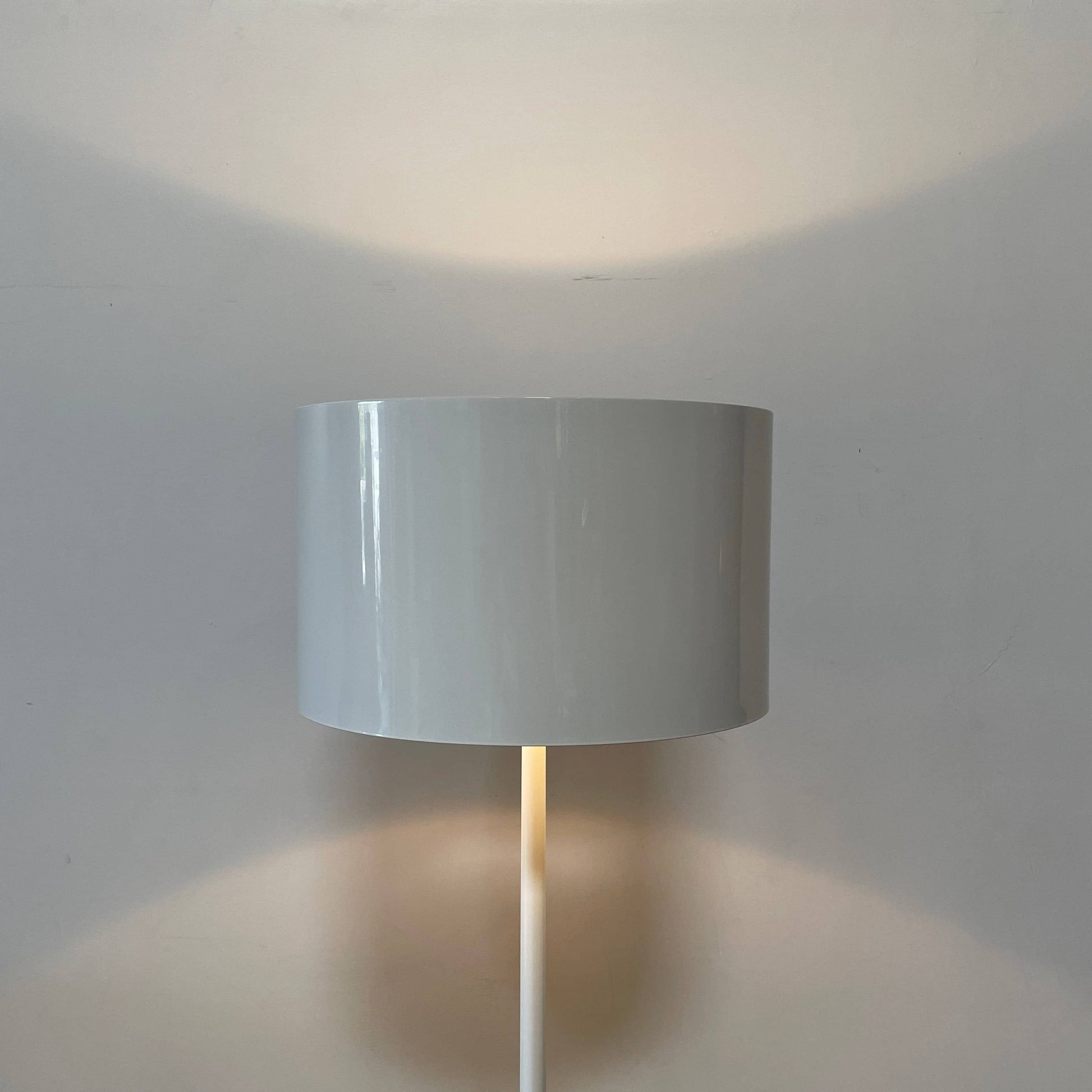 A modern Flos Spun Floor Light with a spun aluminum frame and a white base and shade.