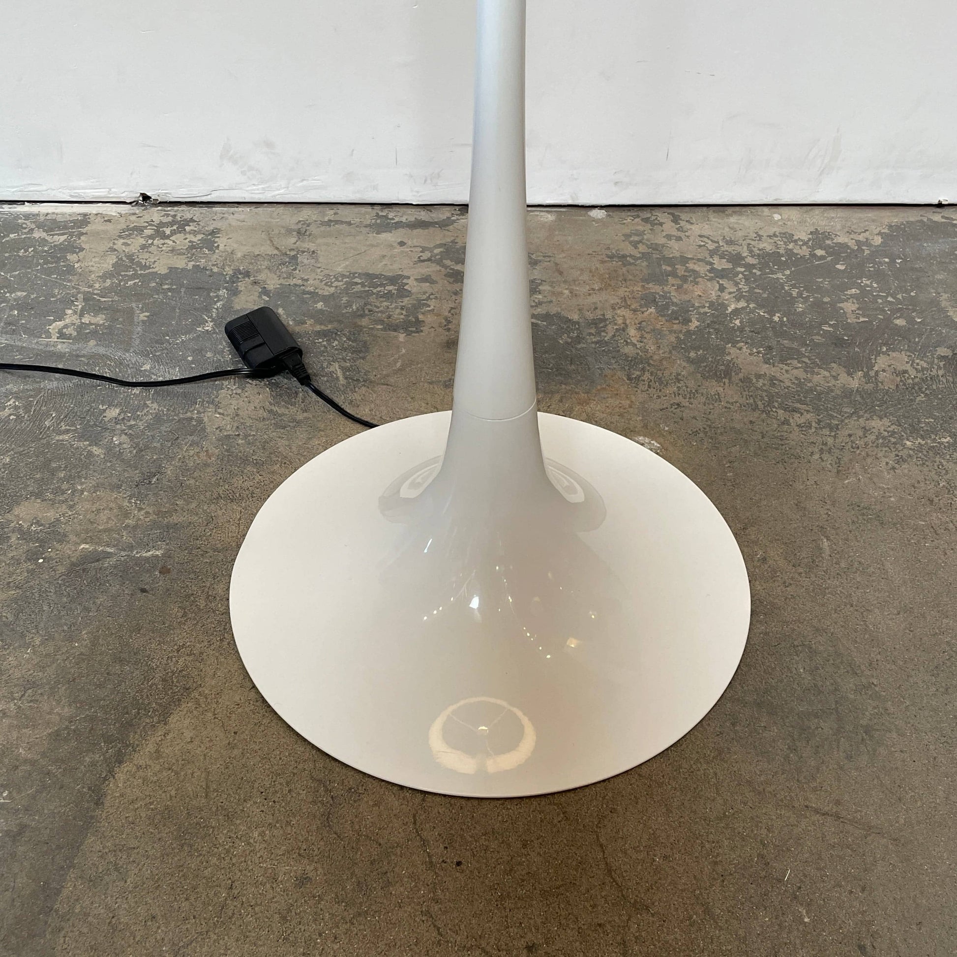 A modern Flos Spun Floor Light with a spun aluminum frame and a white base and shade.