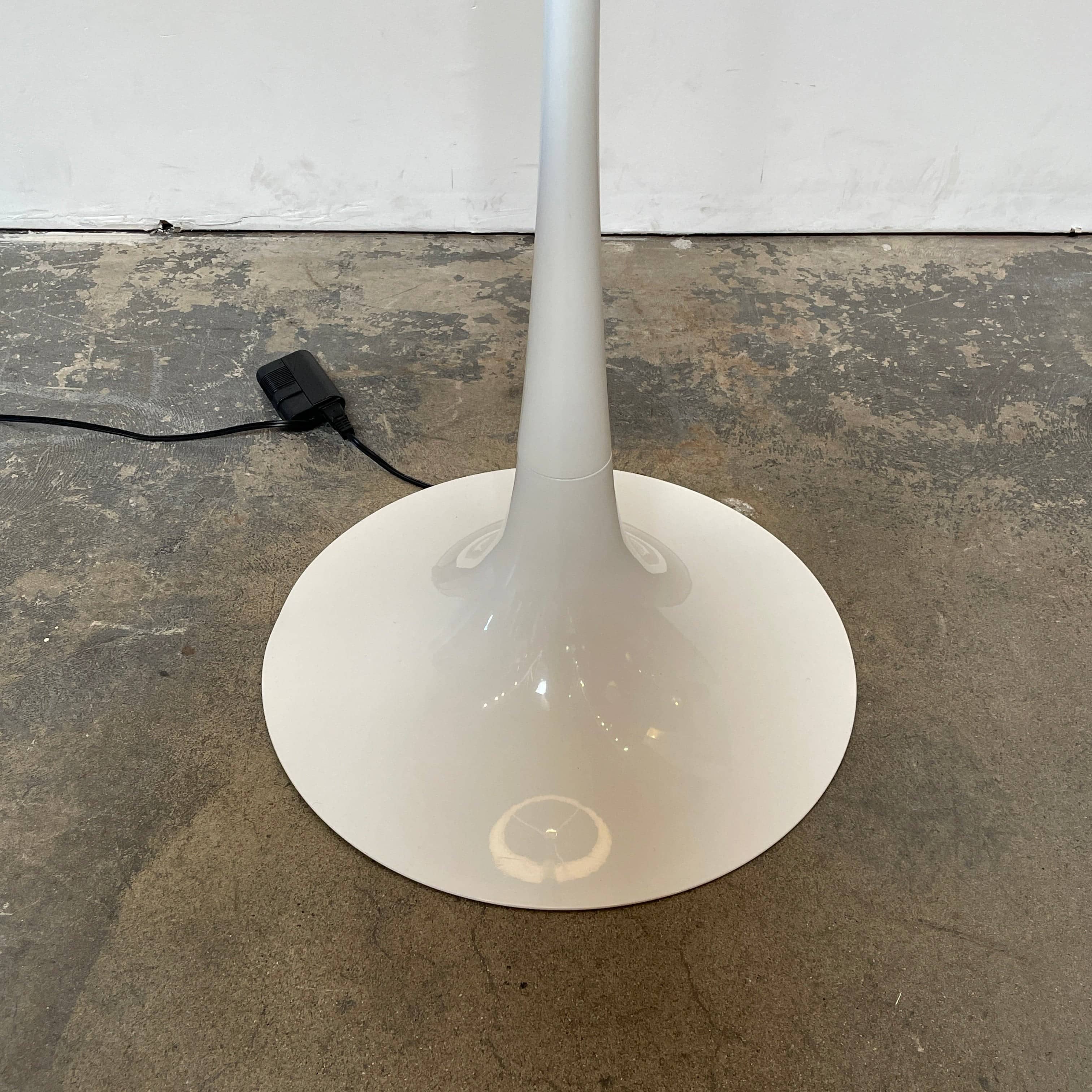A modern Flos Spun Floor Light with a spun aluminum frame and a white base and shade.