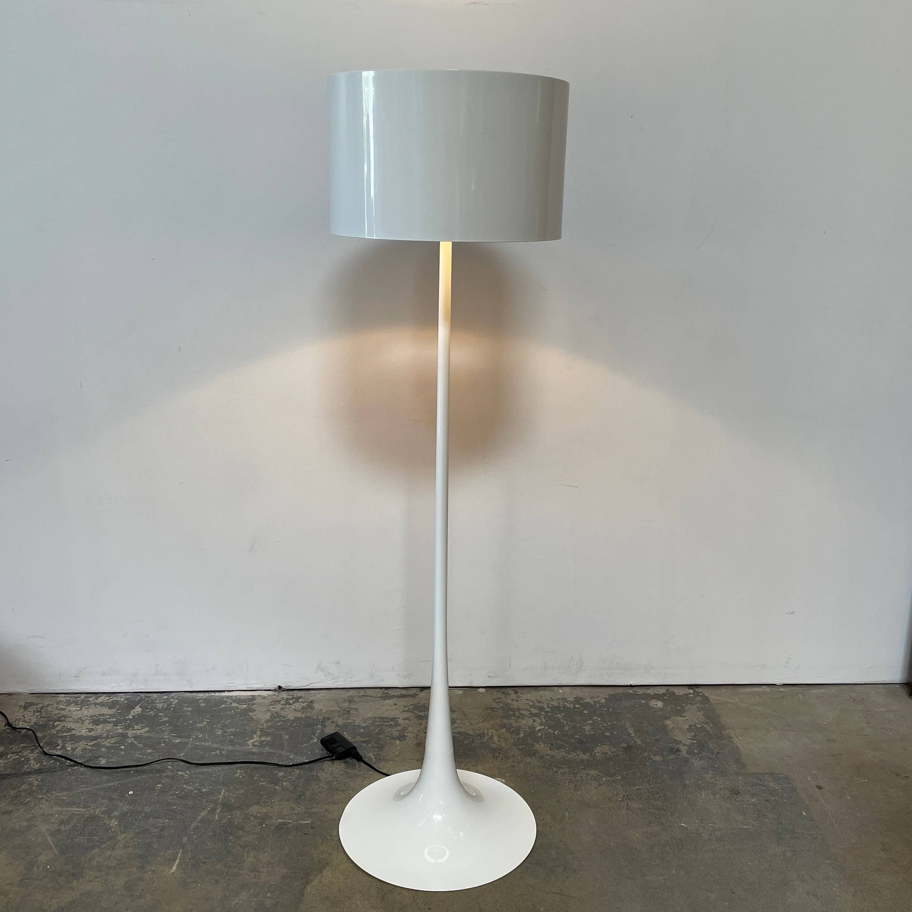 A modern Flos Spun Floor Light with a spun aluminum frame and a white base and shade.