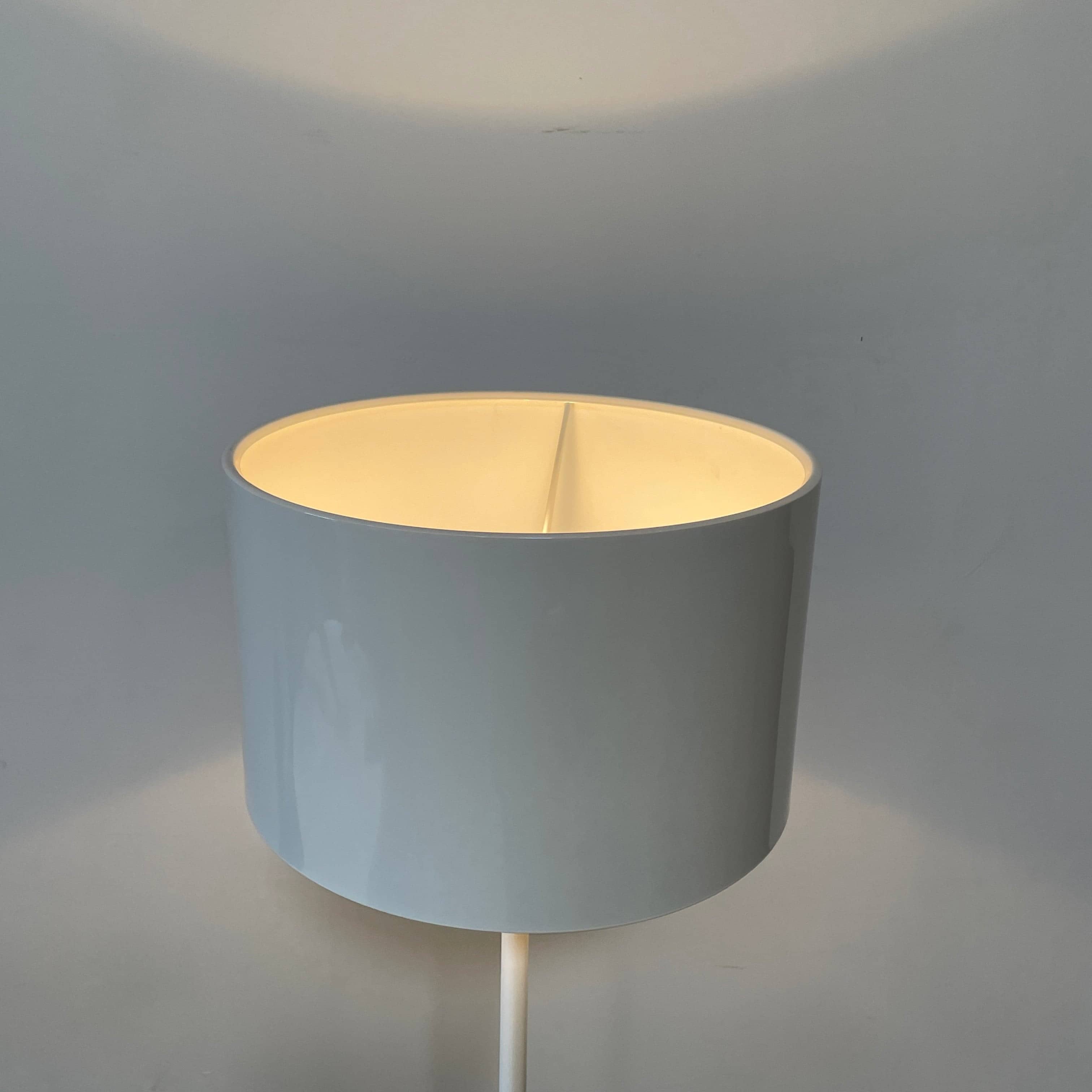 A modern Flos Spun Floor Light with a spun aluminum frame and a white base and shade.