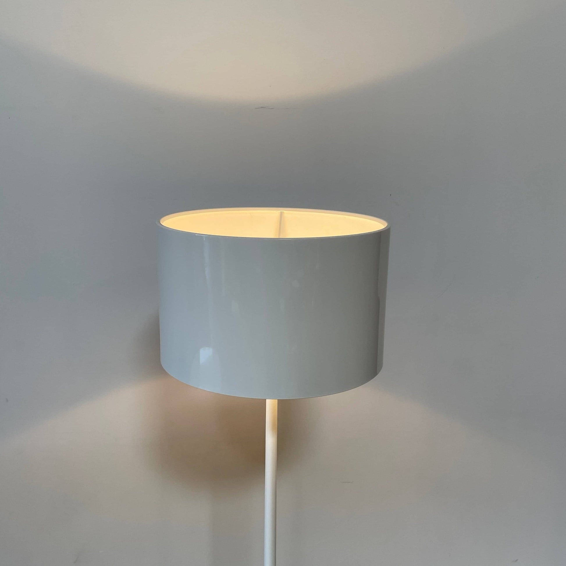 A modern Flos Spun Floor Light with a spun aluminum frame and a white base and shade.
