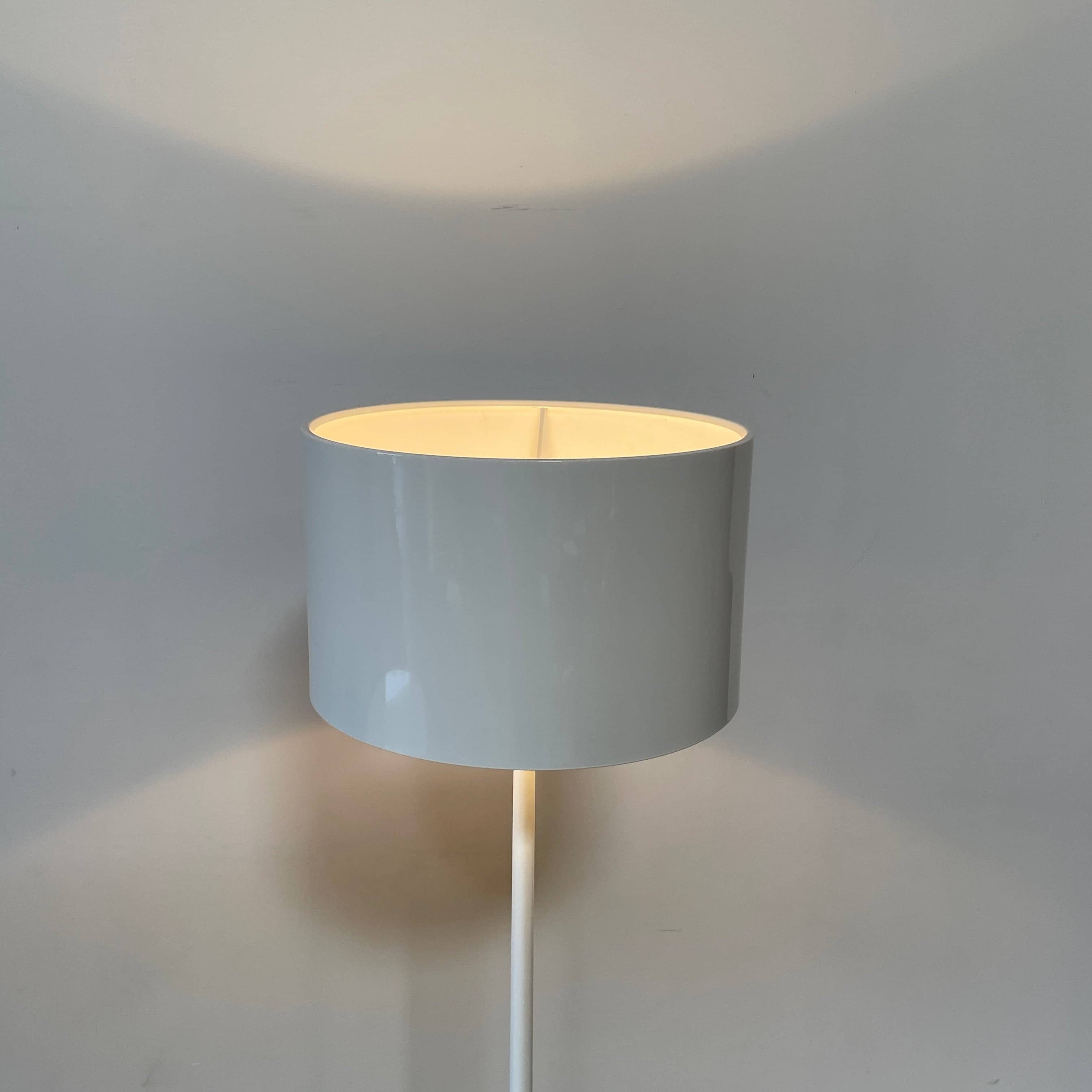 A modern Flos Spun Floor Light with a spun aluminum frame and a white base and shade.