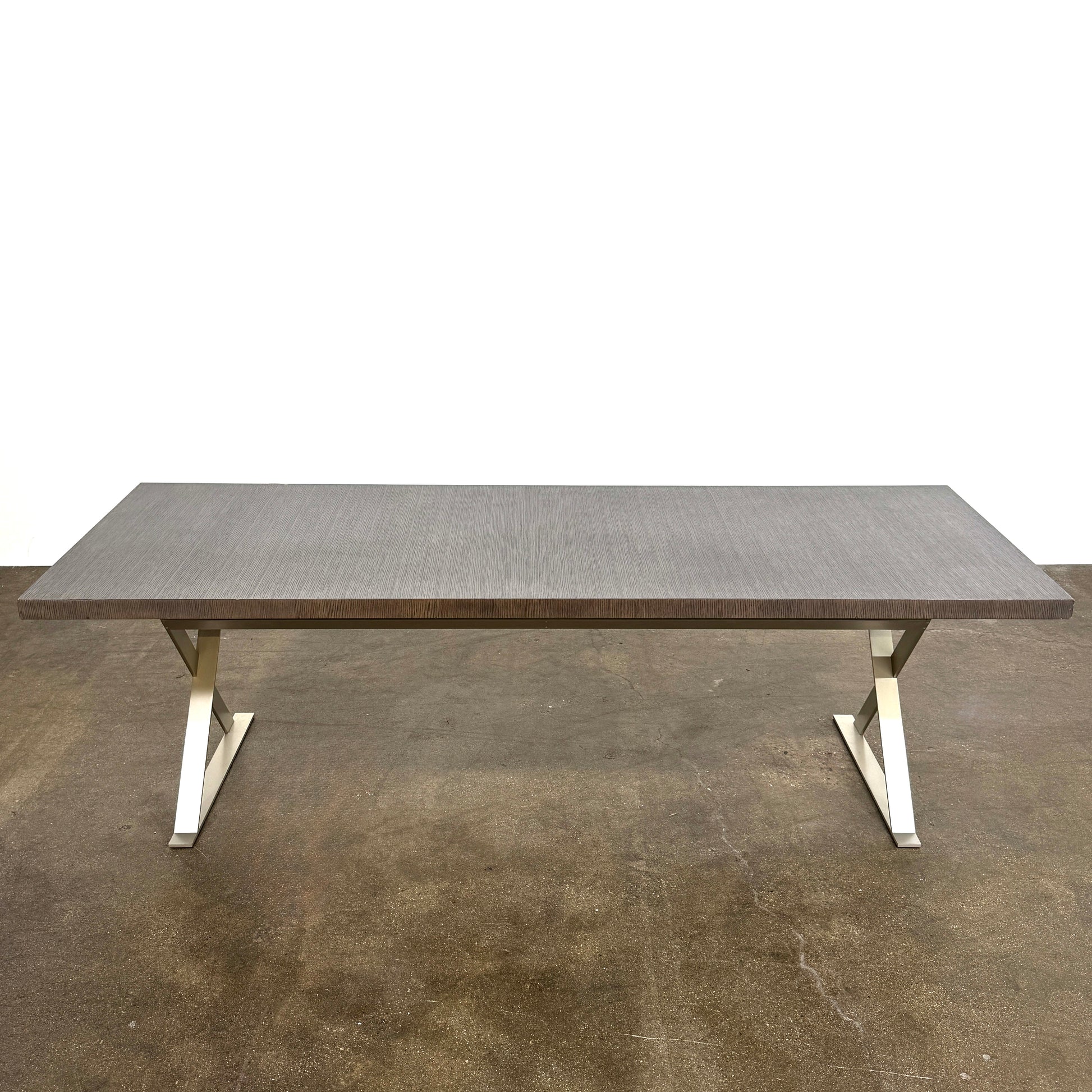 The Maxalto Max Table Grey Oak by Maxalto features a grey oak wooden top, metal legs, and an angular modern design—ideal for enhancing any dining space. Displayed on a plain white background.