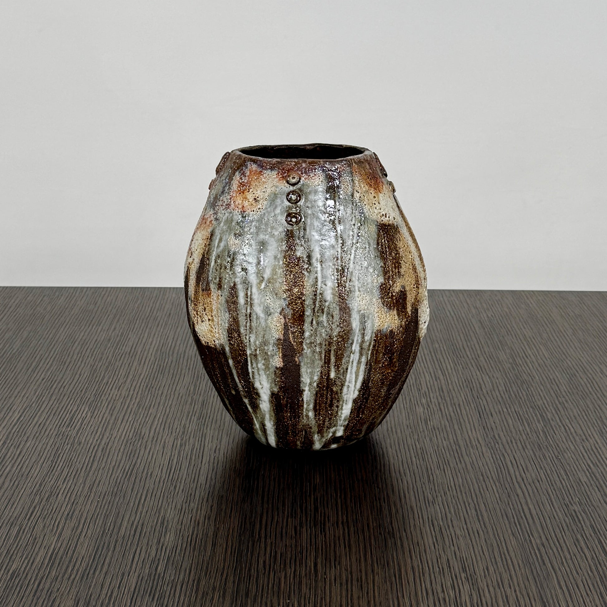 A hand-built dark clay Sofi Ceramics Ocean Vase, Tall by Artist, with irregular brown, black, and white glaze and small circular patterns near the top, set against a plain white background.
