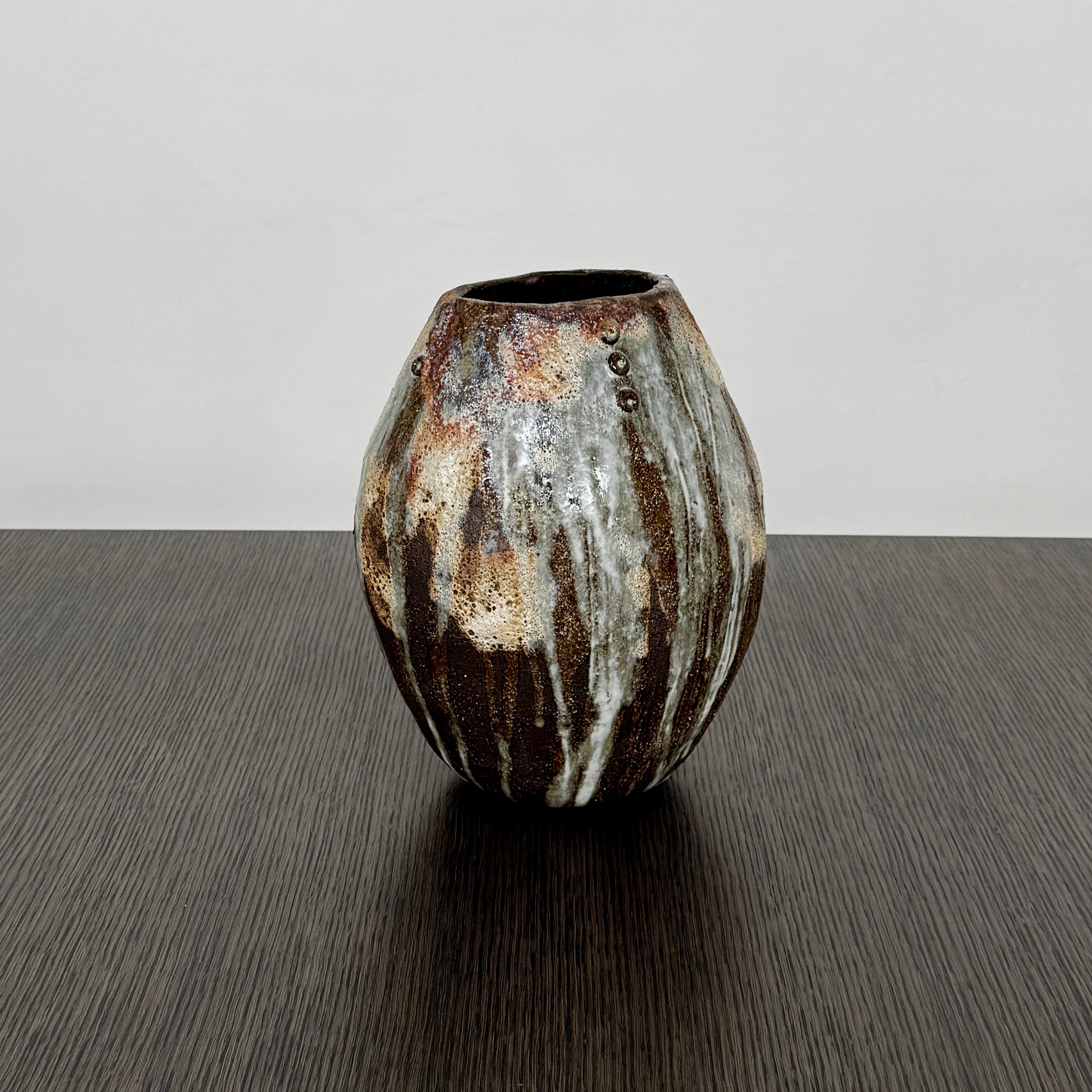 A hand-built dark clay Sofi Ceramics Ocean Vase, Tall by Artist, with irregular brown, black, and white glaze and small circular patterns near the top, set against a plain white background.