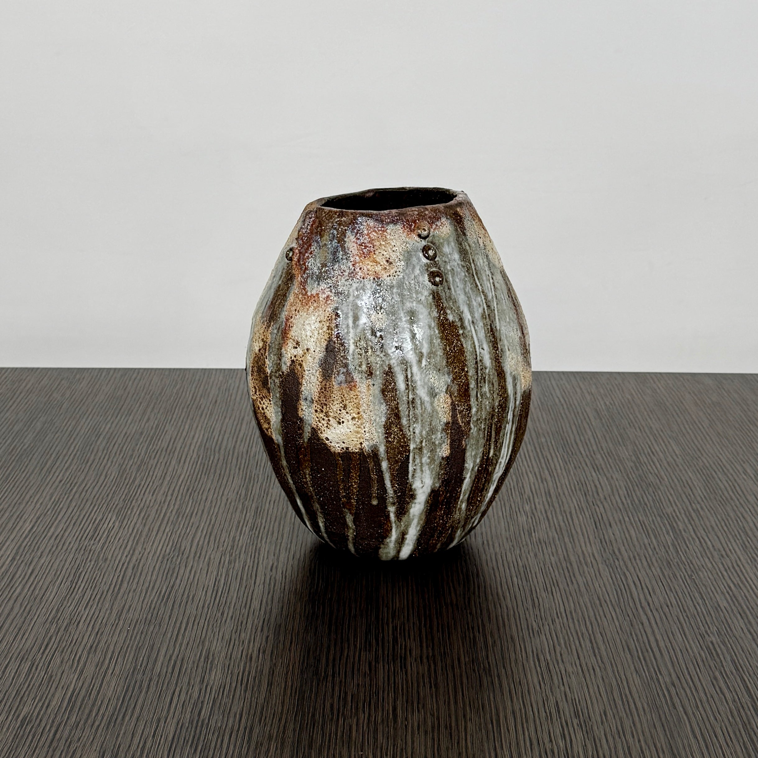 A hand-built dark clay Sofi Ceramics Ocean Vase, Tall by Artist, with irregular brown, black, and white glaze and small circular patterns near the top, set against a plain white background.