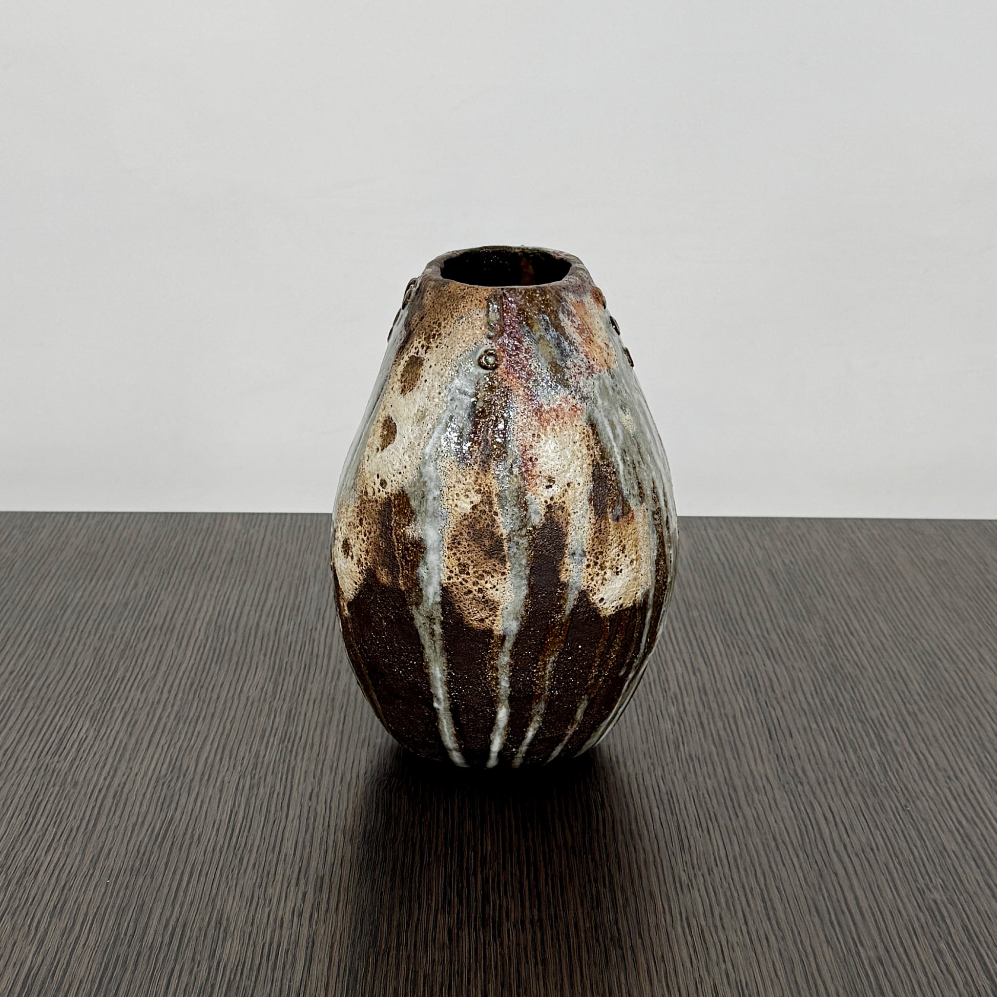 A hand-built dark clay Sofi Ceramics Ocean Vase, Tall by Artist, with irregular brown, black, and white glaze and small circular patterns near the top, set against a plain white background.