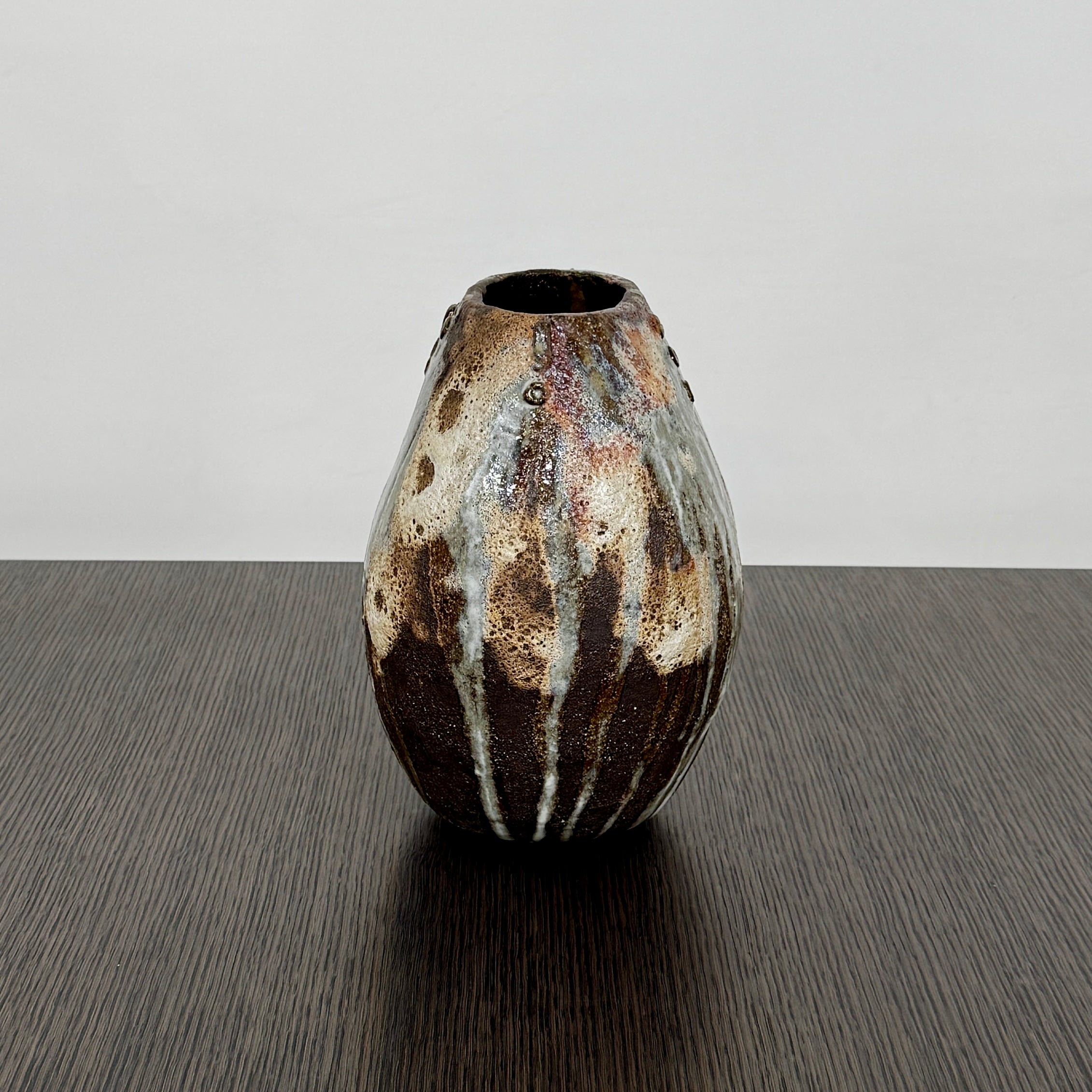 A hand-built dark clay Sofi Ceramics Ocean Vase, Tall by Artist, with irregular brown, black, and white glaze and small circular patterns near the top, set against a plain white background.