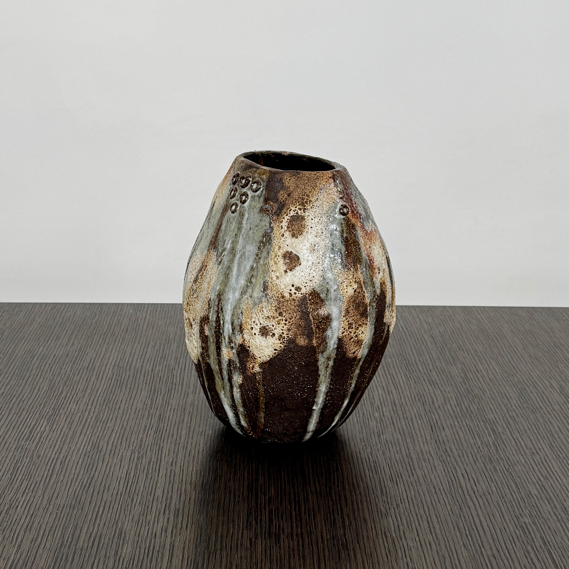 A hand-built dark clay Sofi Ceramics Ocean Vase, Tall by Artist, with irregular brown, black, and white glaze and small circular patterns near the top, set against a plain white background.