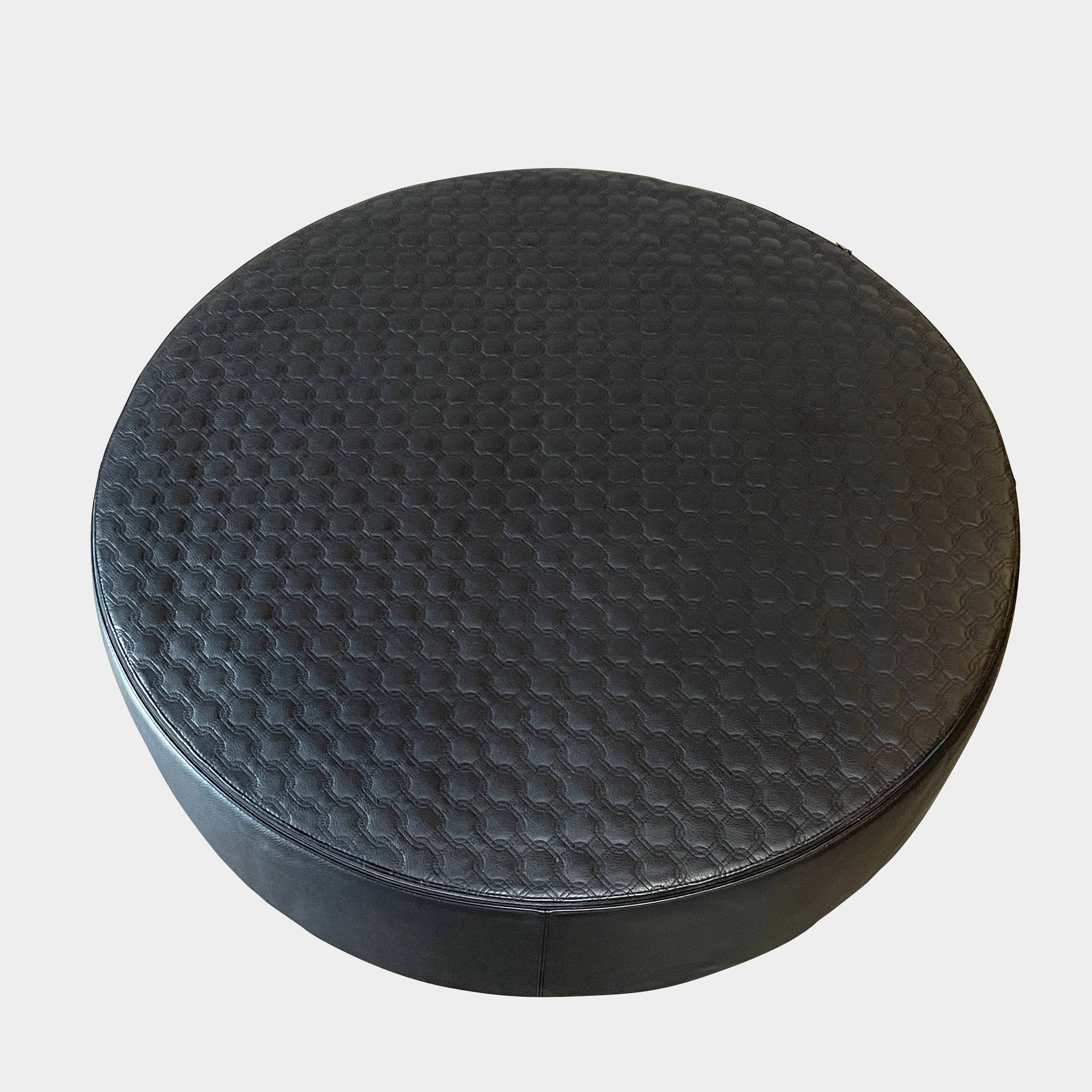 A round black Minotti Yang Leather Ottoman on a white background.