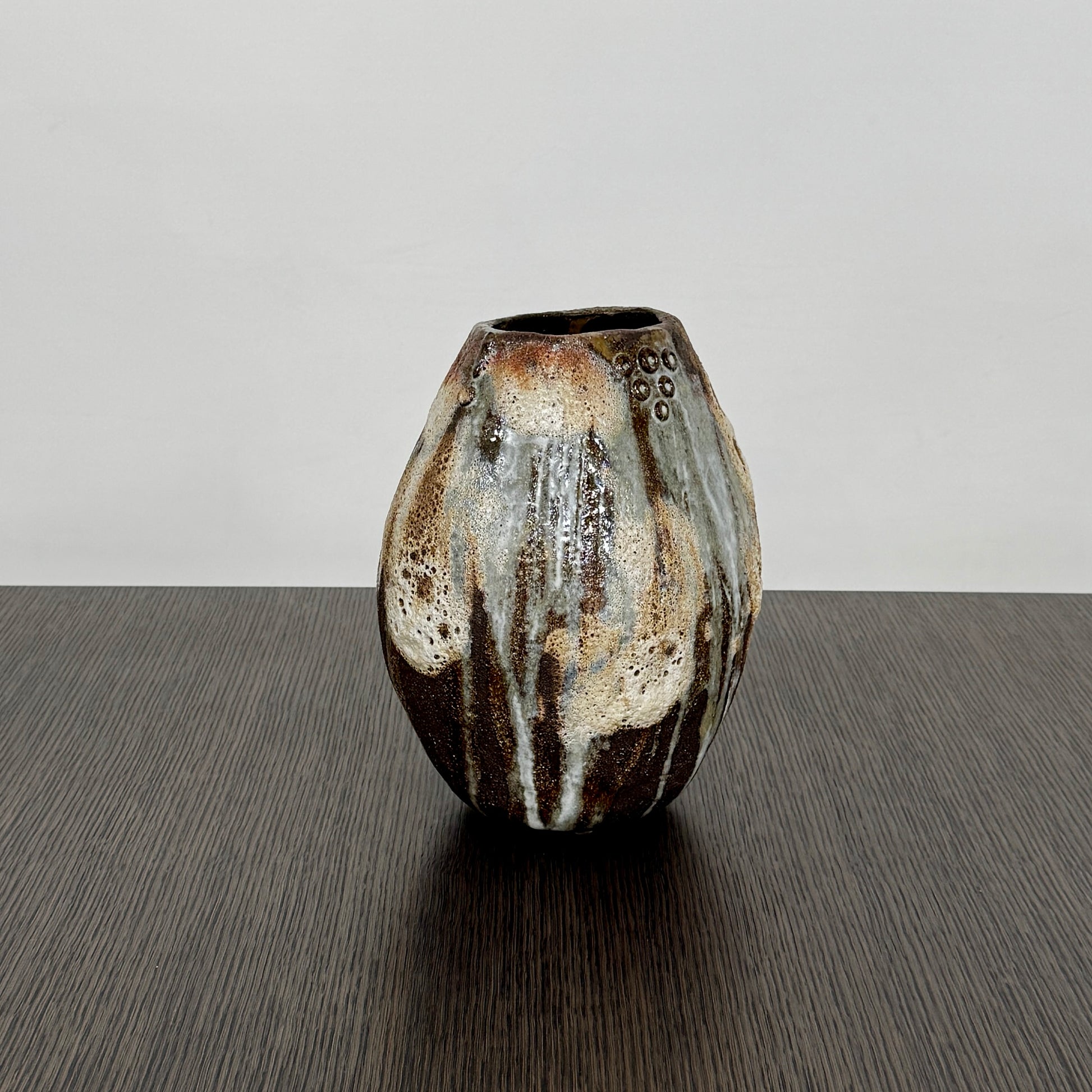 A hand-built dark clay Sofi Ceramics Ocean Vase, Tall by Artist, with irregular brown, black, and white glaze and small circular patterns near the top, set against a plain white background.