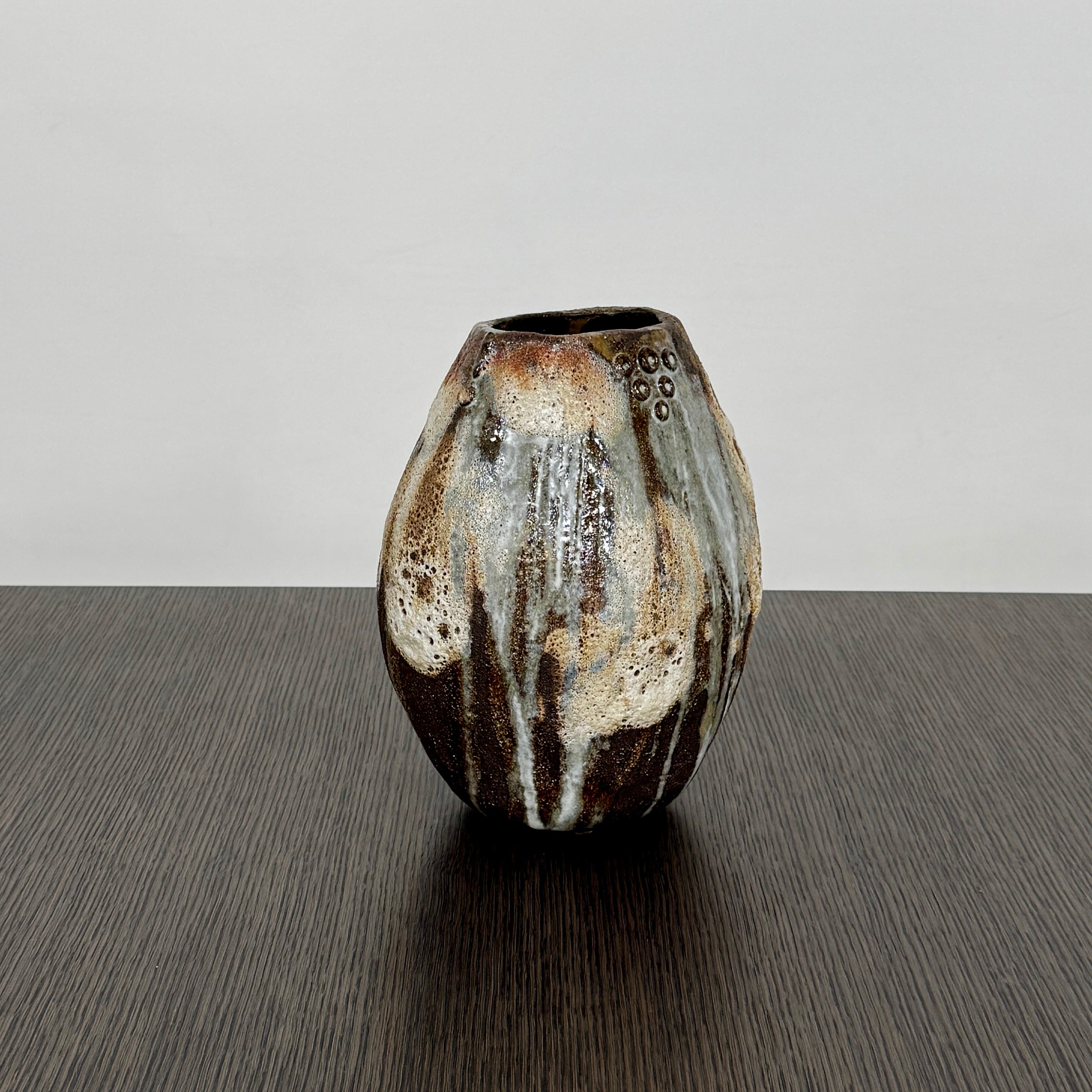 A hand-built dark clay Sofi Ceramics Ocean Vase, Tall by Artist, with irregular brown, black, and white glaze and small circular patterns near the top, set against a plain white background.