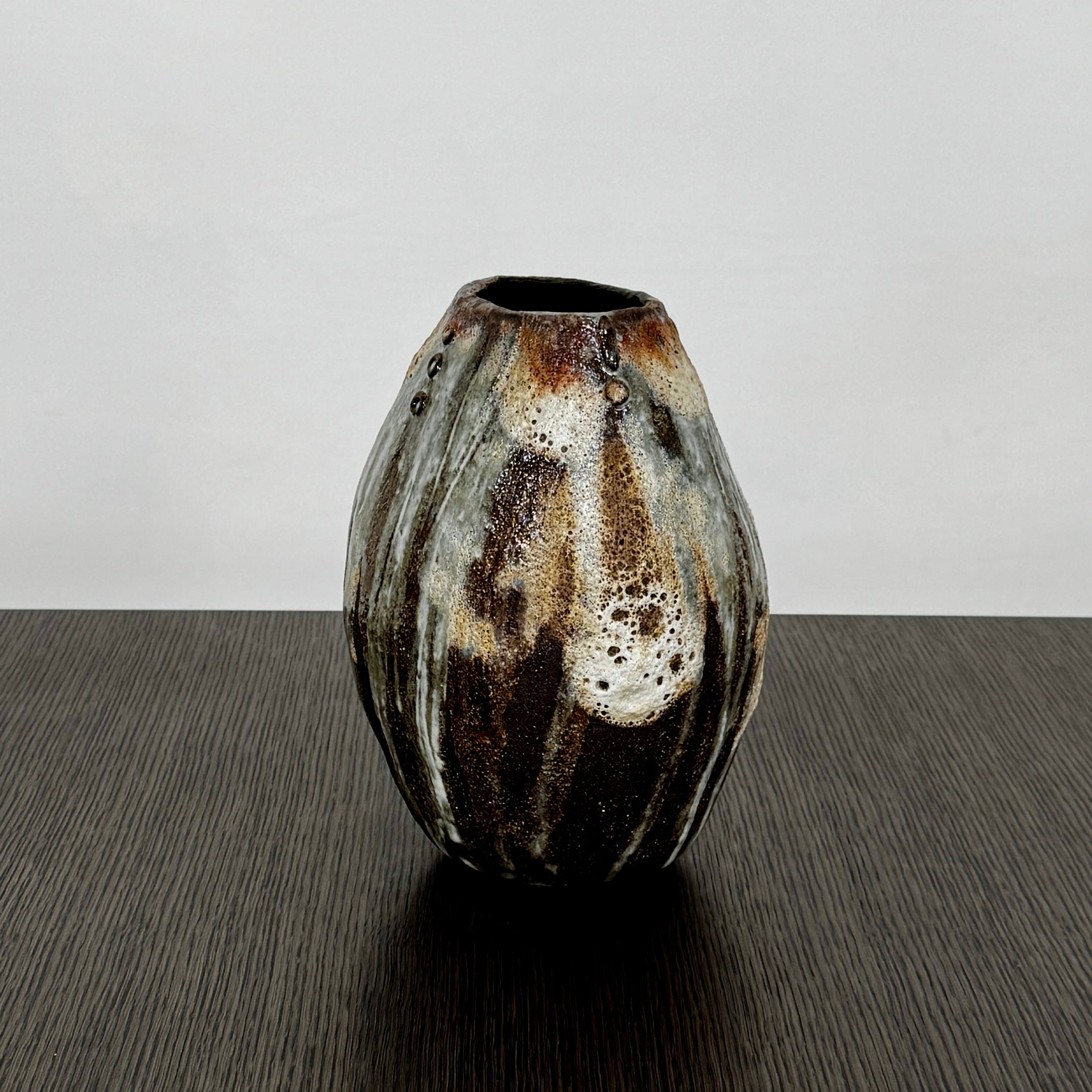 A hand-built dark clay Sofi Ceramics Ocean Vase, Tall by Artist, with irregular brown, black, and white glaze and small circular patterns near the top, set against a plain white background.