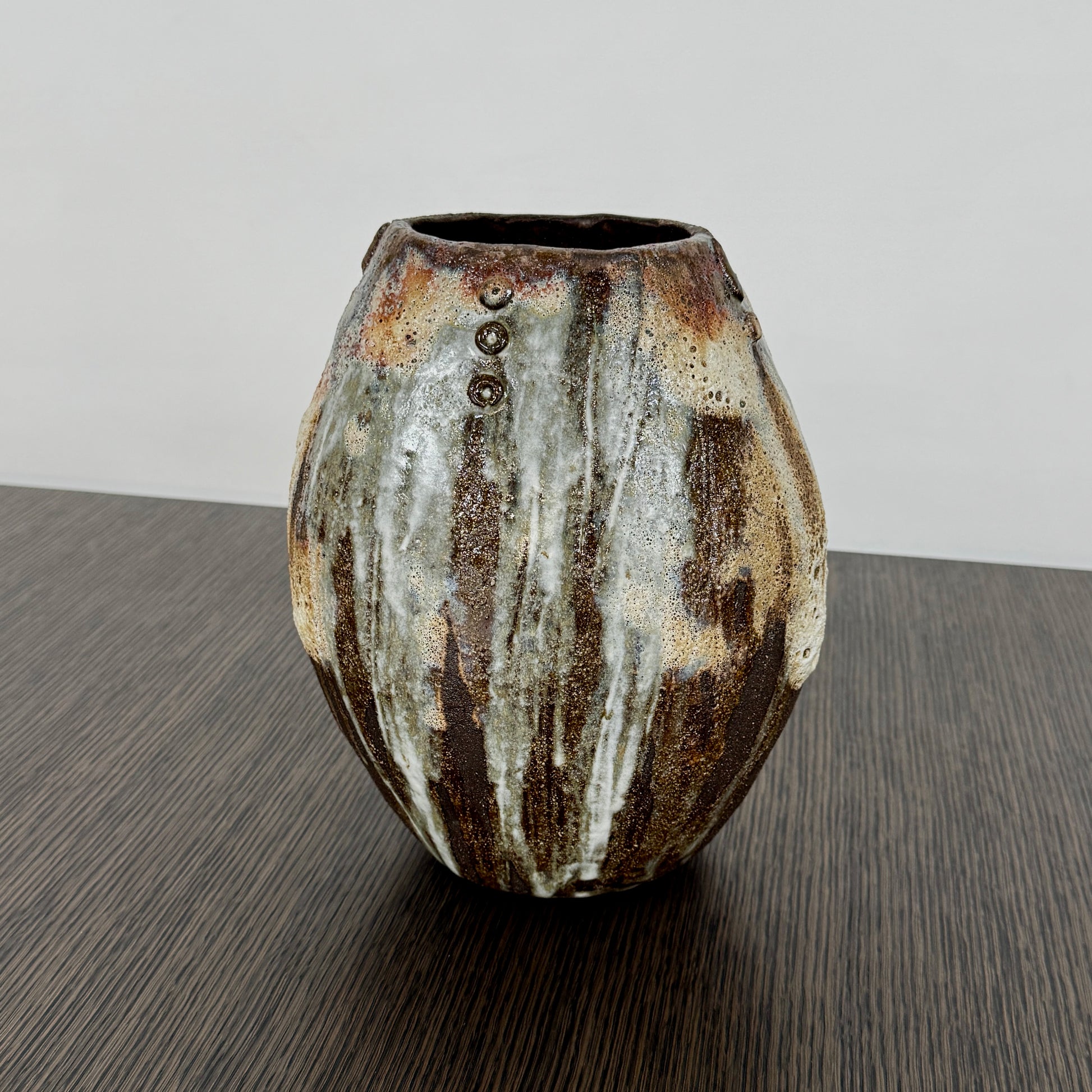A hand-built dark clay Sofi Ceramics Ocean Vase, Tall by Artist, with irregular brown, black, and white glaze and small circular patterns near the top, set against a plain white background.