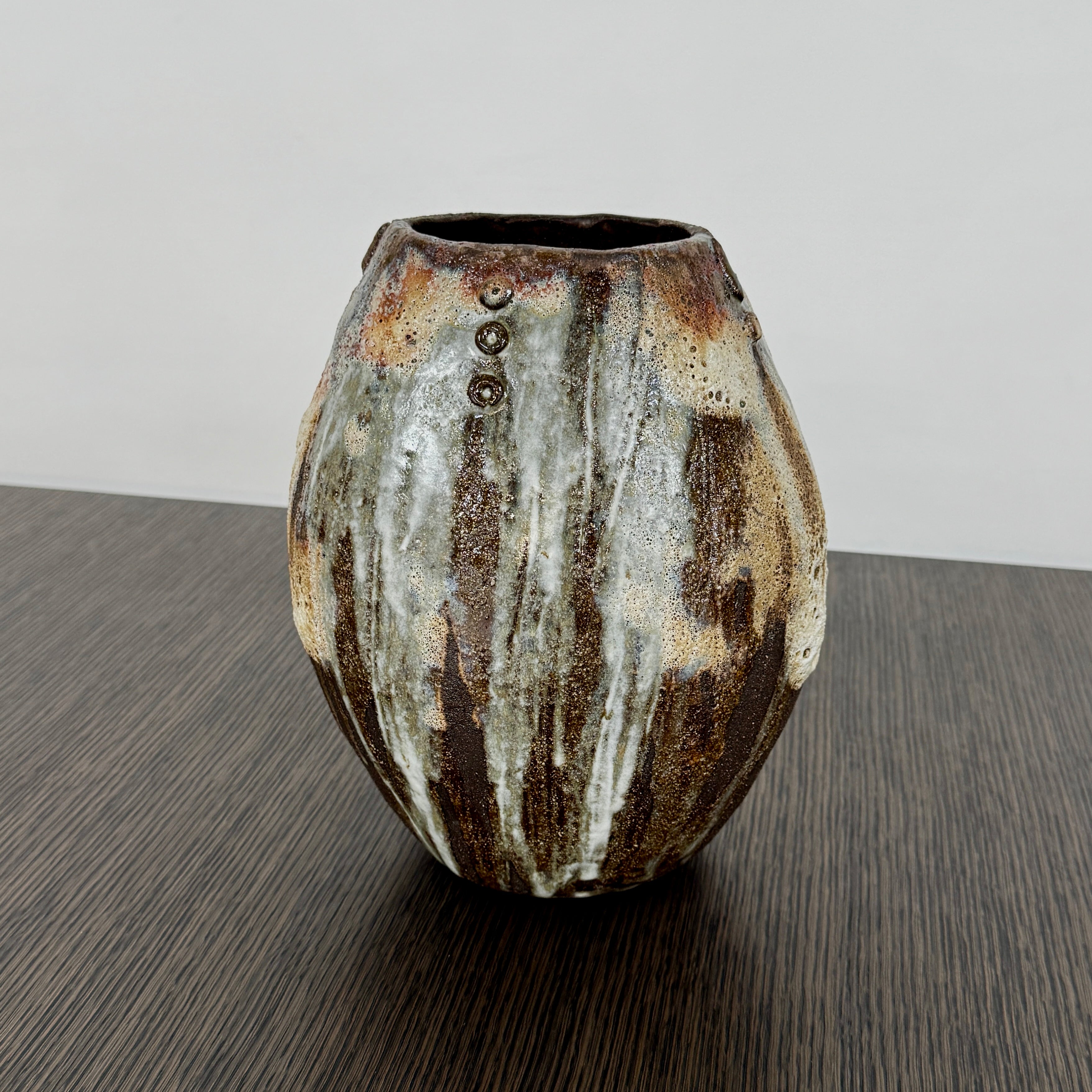 A hand-built dark clay Sofi Ceramics Ocean Vase, Tall by Artist, with irregular brown, black, and white glaze and small circular patterns near the top, set against a plain white background.