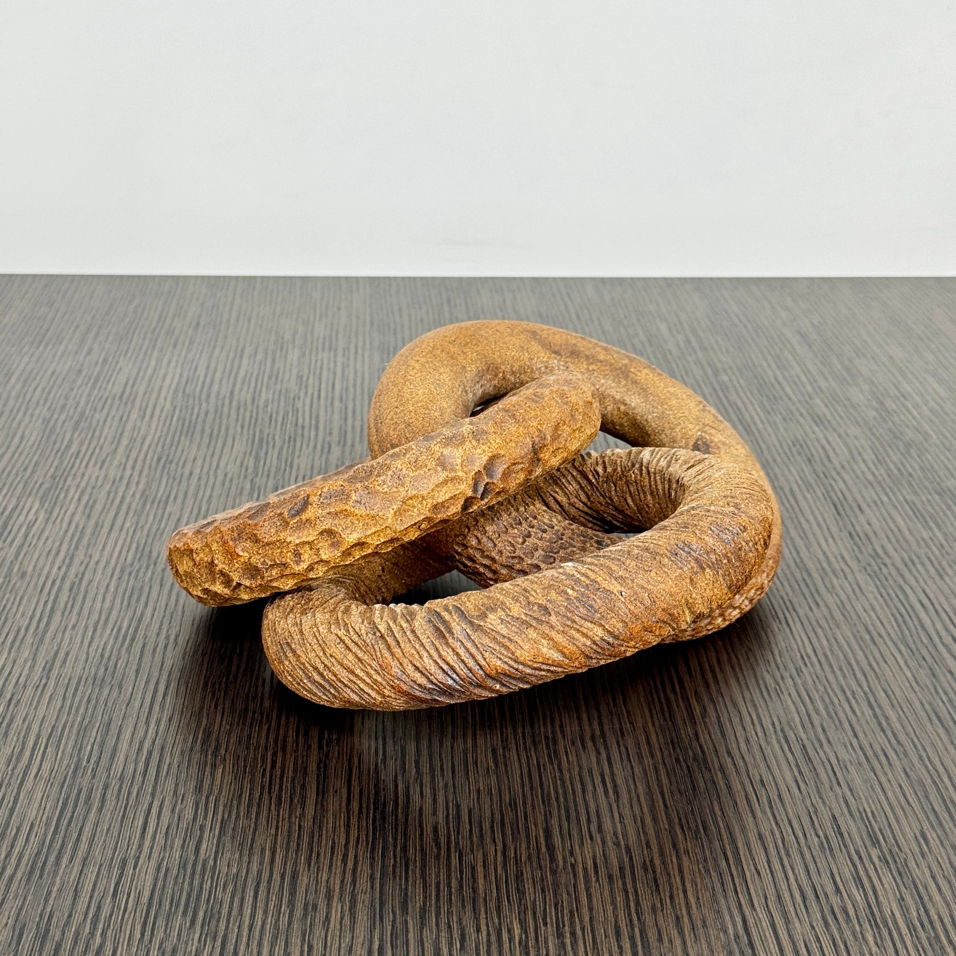 The Artist Sofi Ceramics Carved Rings feature two interlocking brown wooden rings with varied textures, evocative of ceramic artistry, shown on a plain white background.