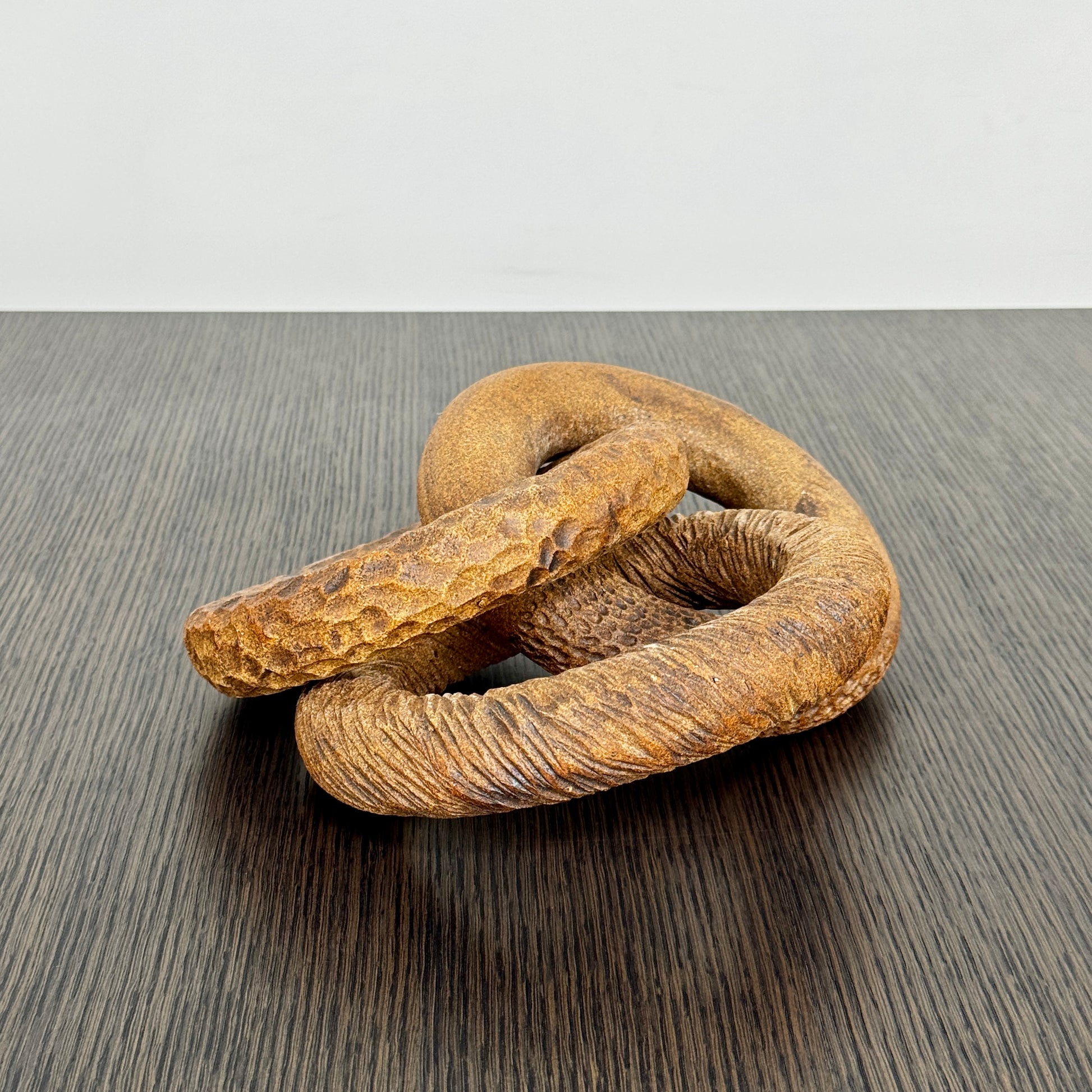 The Artist Sofi Ceramics Carved Rings feature two interlocking brown wooden rings with varied textures, evocative of ceramic artistry, shown on a plain white background.