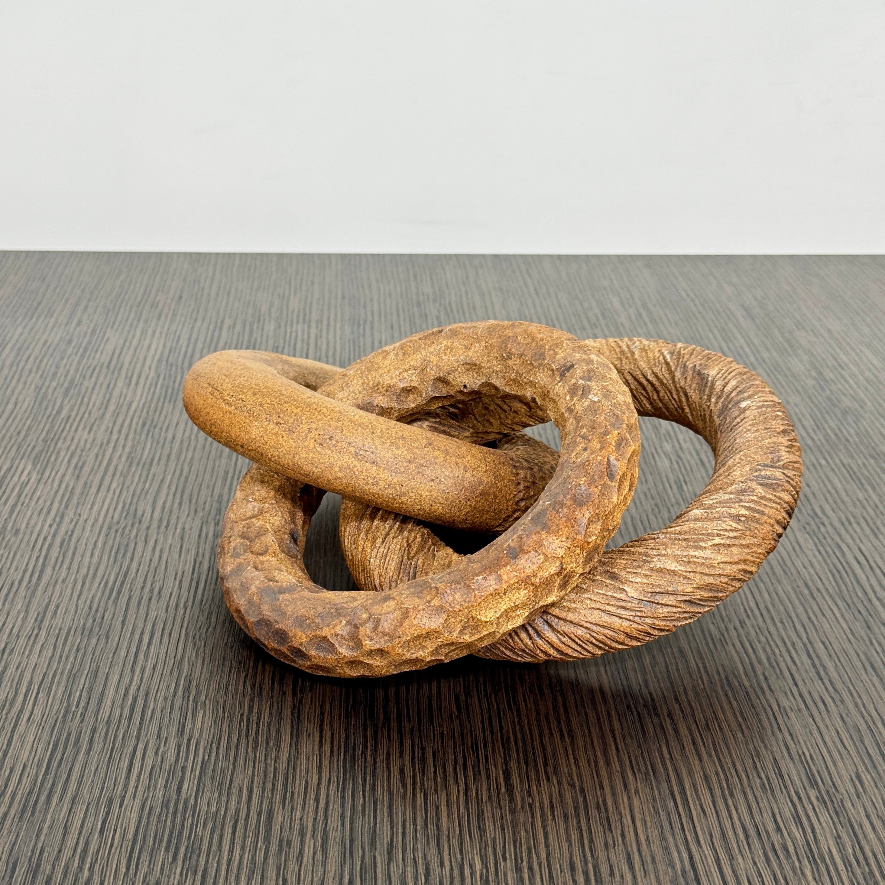 The Artist Sofi Ceramics Carved Rings feature two interlocking brown wooden rings with varied textures, evocative of ceramic artistry, shown on a plain white background.