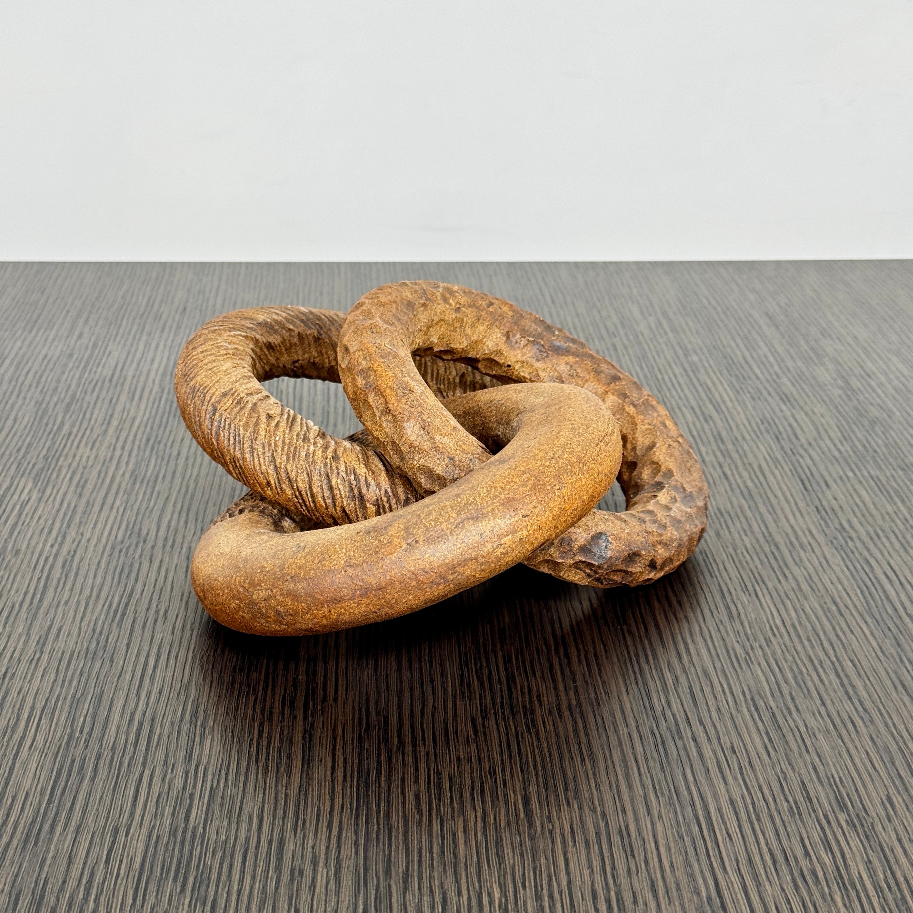 The Artist Sofi Ceramics Carved Rings feature two interlocking brown wooden rings with varied textures, evocative of ceramic artistry, shown on a plain white background.