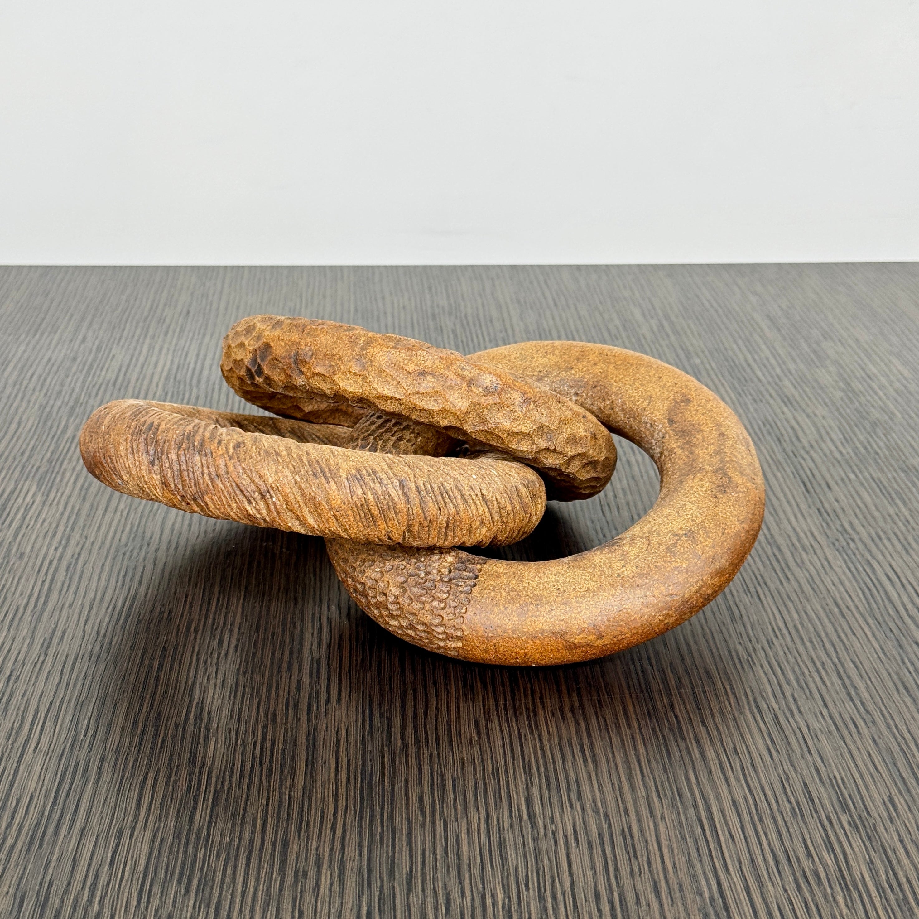 The Artist Sofi Ceramics Carved Rings feature two interlocking brown wooden rings with varied textures, evocative of ceramic artistry, shown on a plain white background.