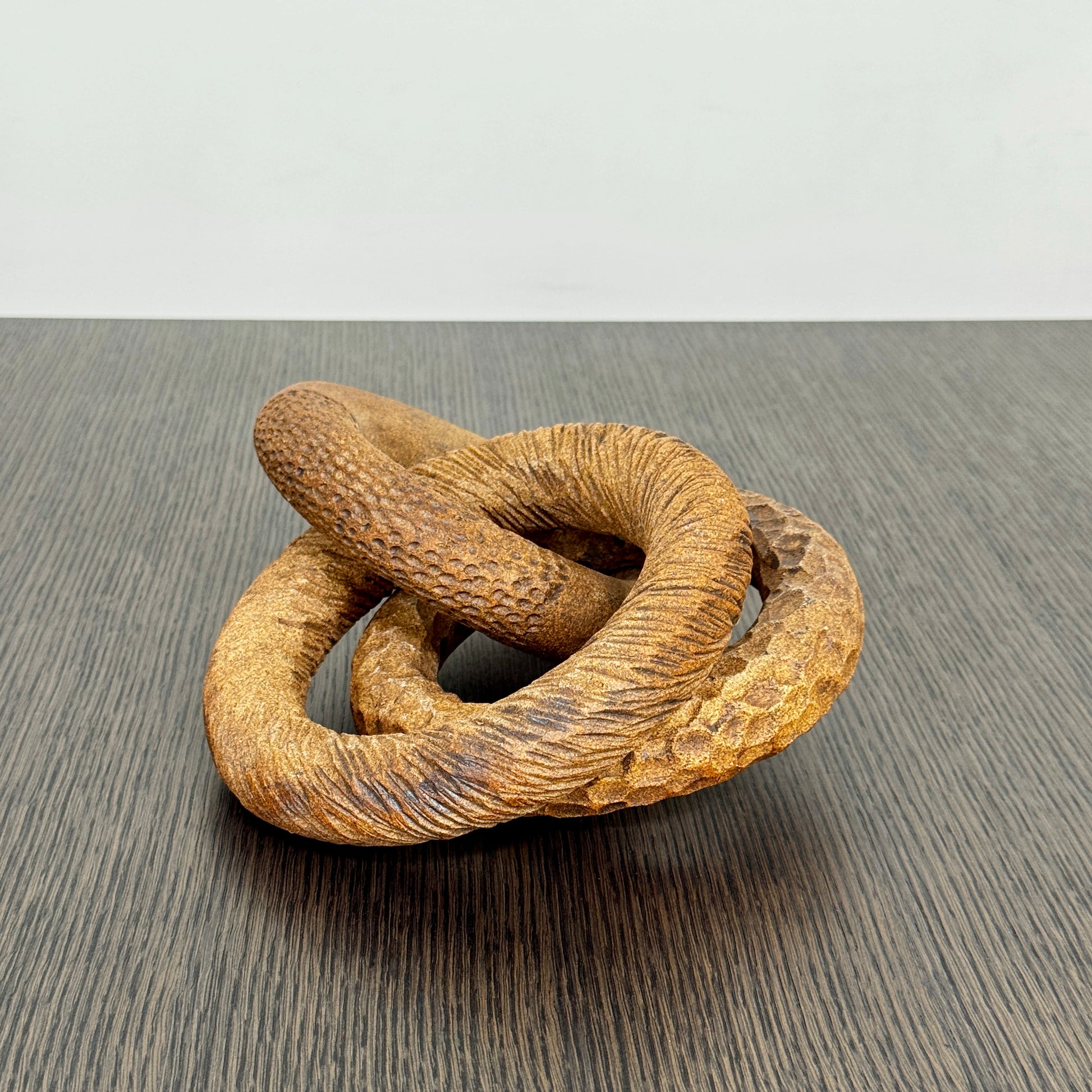 The Artist Sofi Ceramics Carved Rings feature two interlocking brown wooden rings with varied textures, evocative of ceramic artistry, shown on a plain white background.