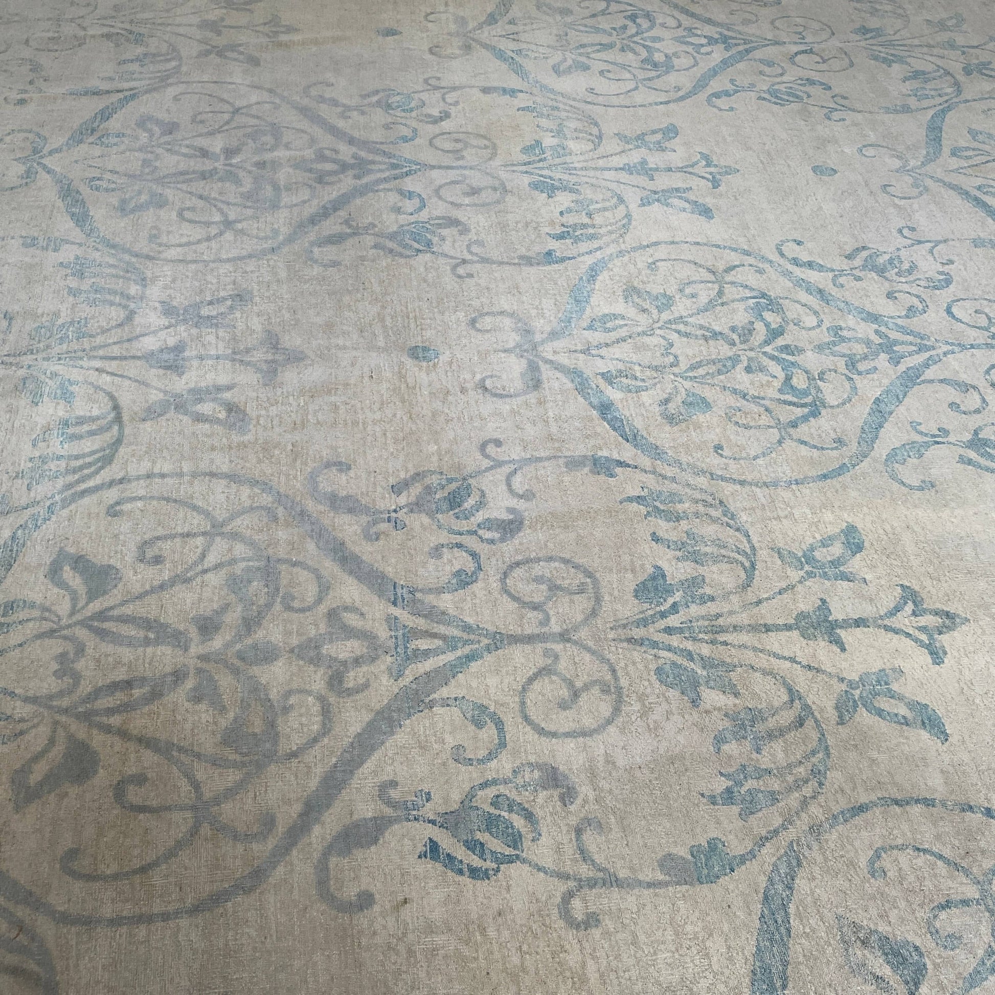 Close-up of a corner of an ornate, traditional Vintage rug with blue patterns on a beige background.