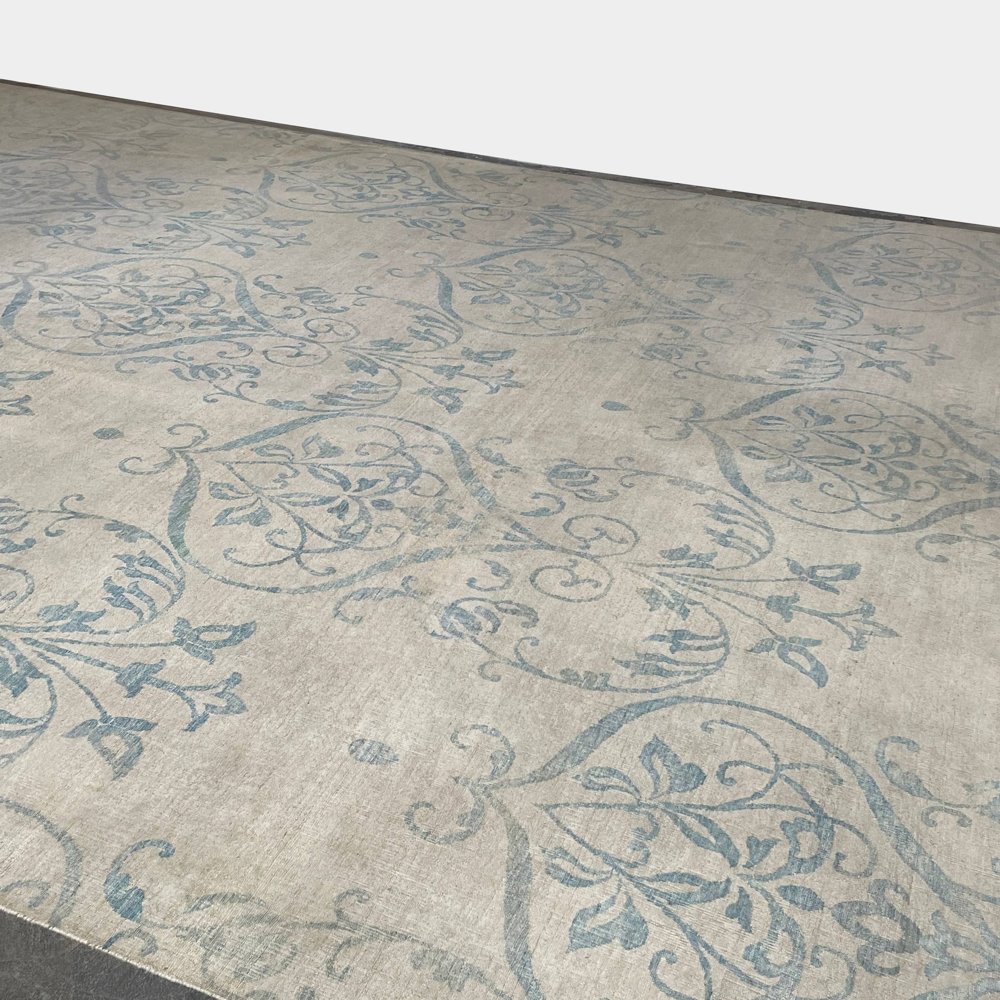 Close-up of a corner of an ornate, traditional Vintage rug with blue patterns on a beige background.