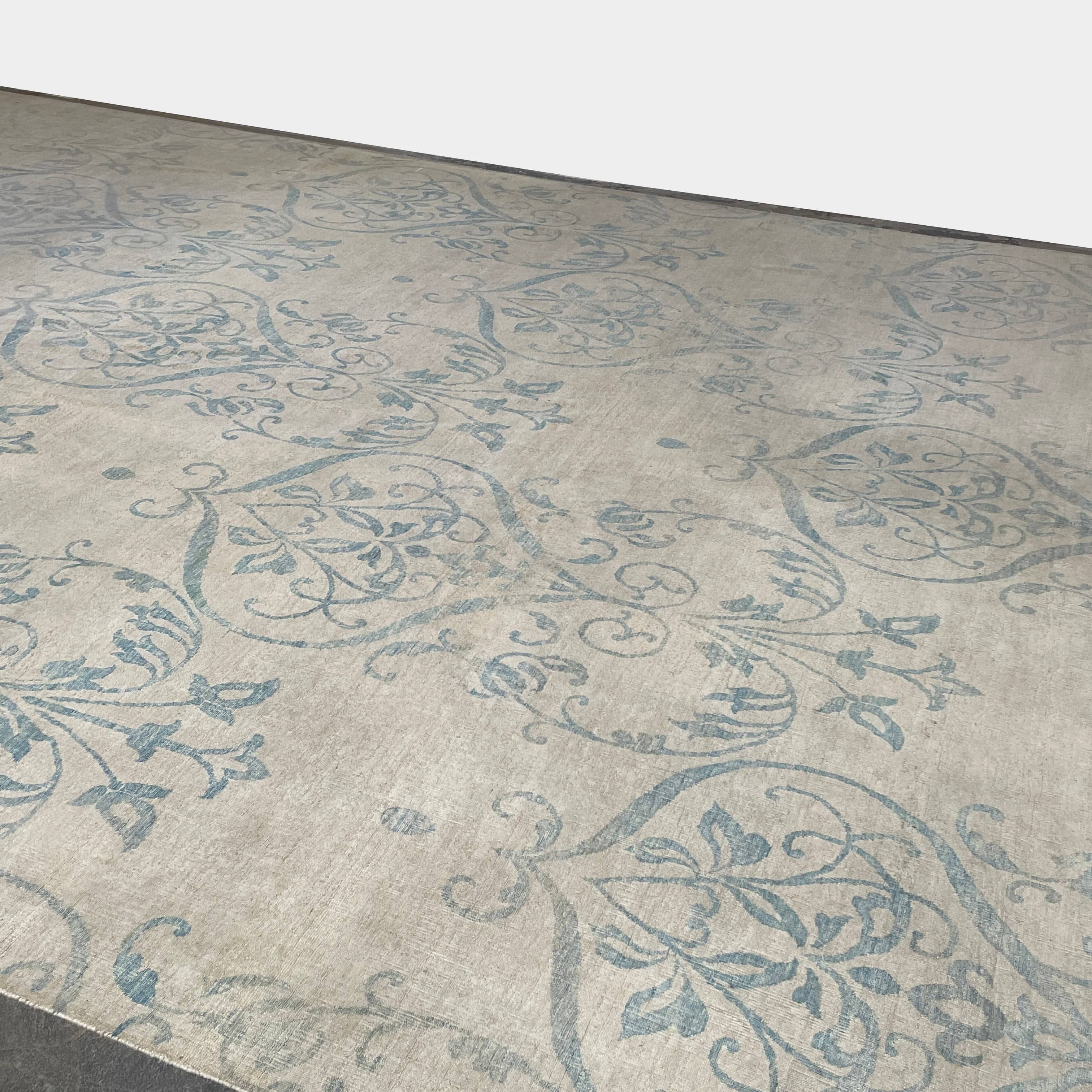 Close-up of a corner of an ornate, traditional Vintage rug with blue patterns on a beige background.