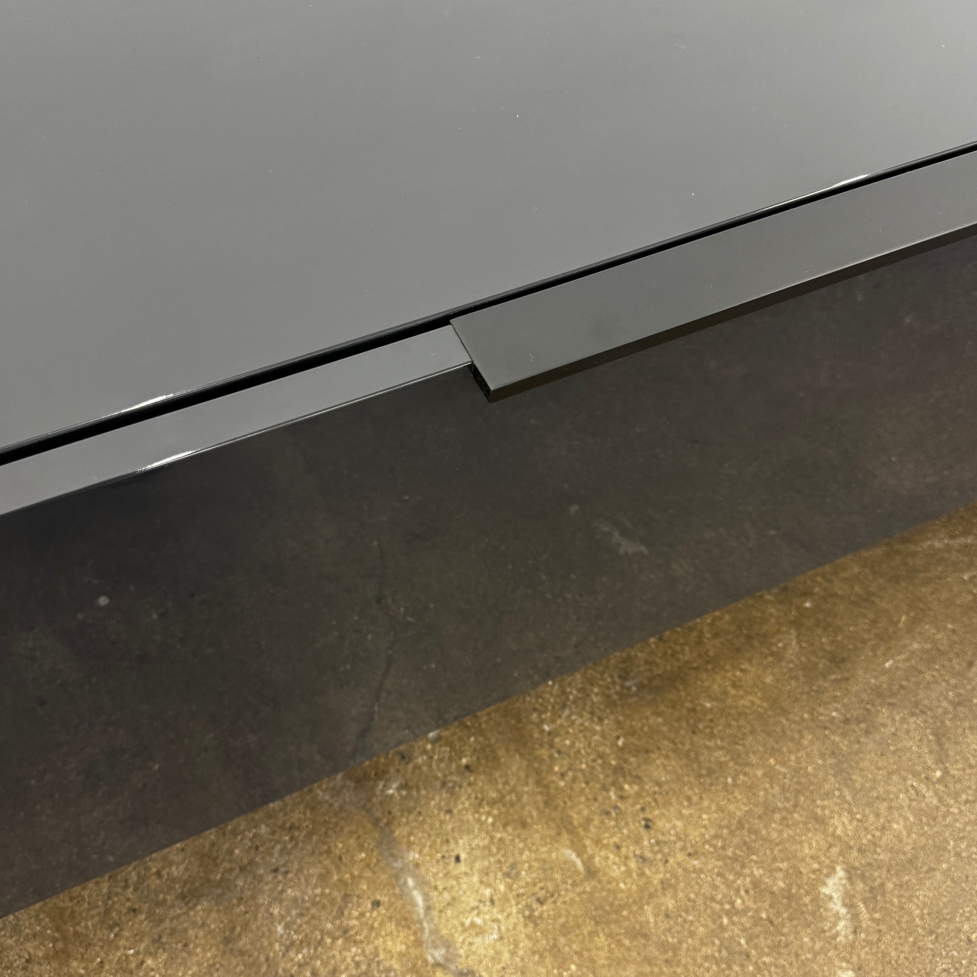 The B&B Italia Athos Console features a modern black rectangular design with a glossy finish and metal legs, showcased against a plain white background.