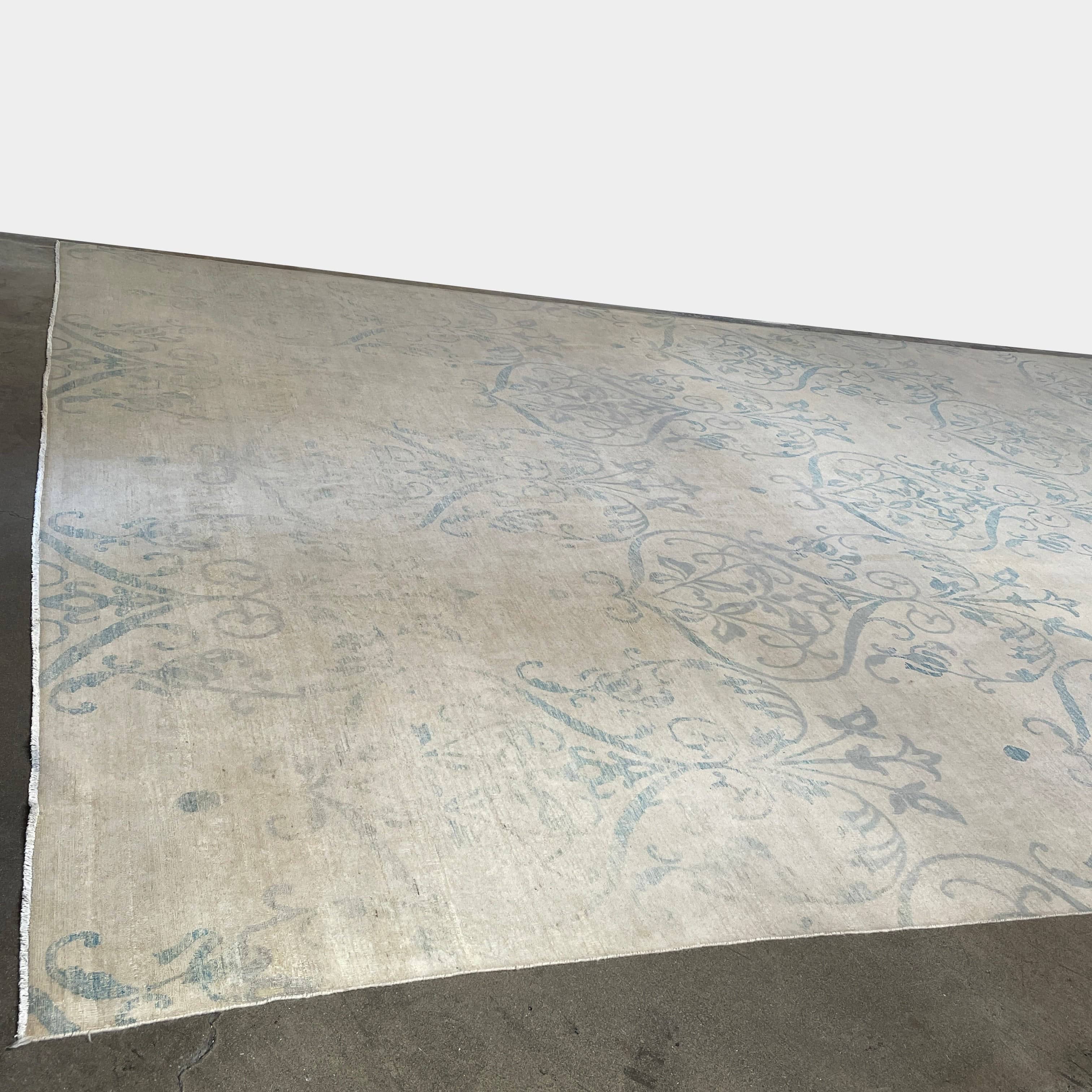 Close-up of a corner of an ornate, traditional Vintage rug with blue patterns on a beige background.