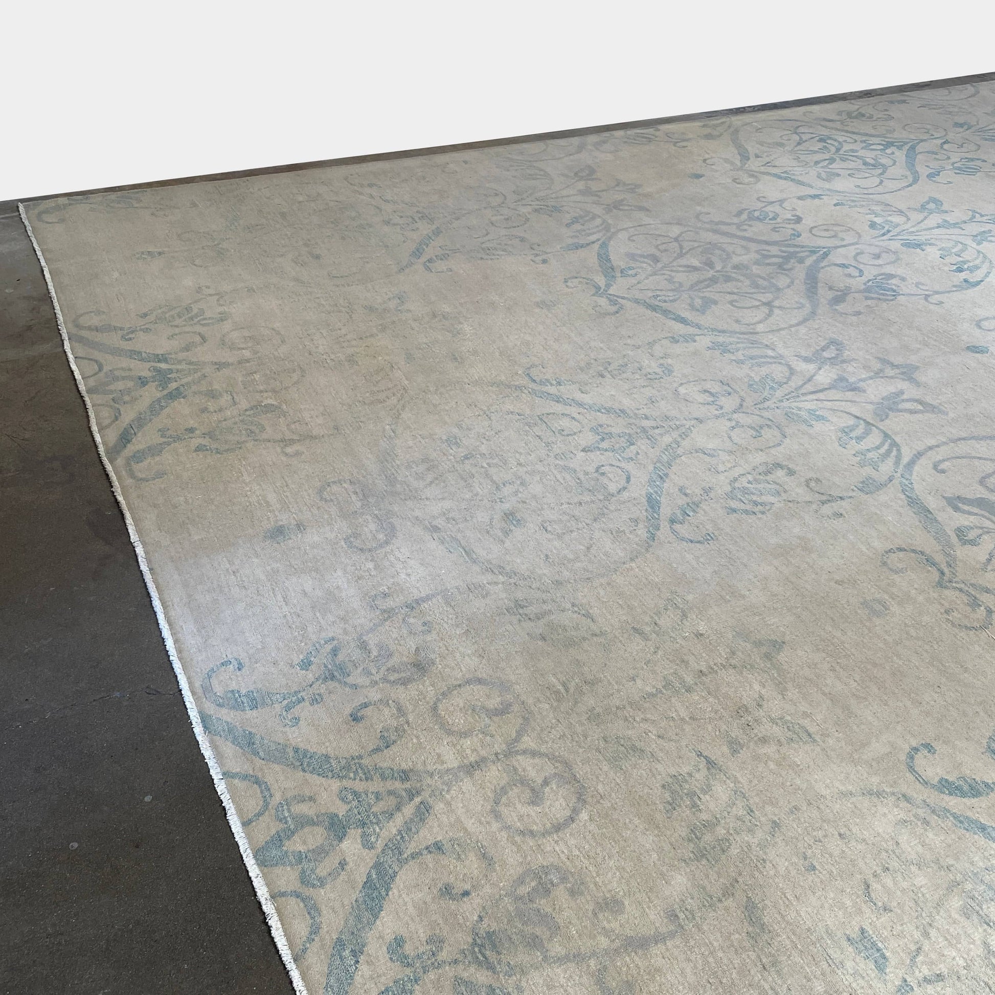 Close-up of a corner of an ornate, traditional Vintage rug with blue patterns on a beige background.