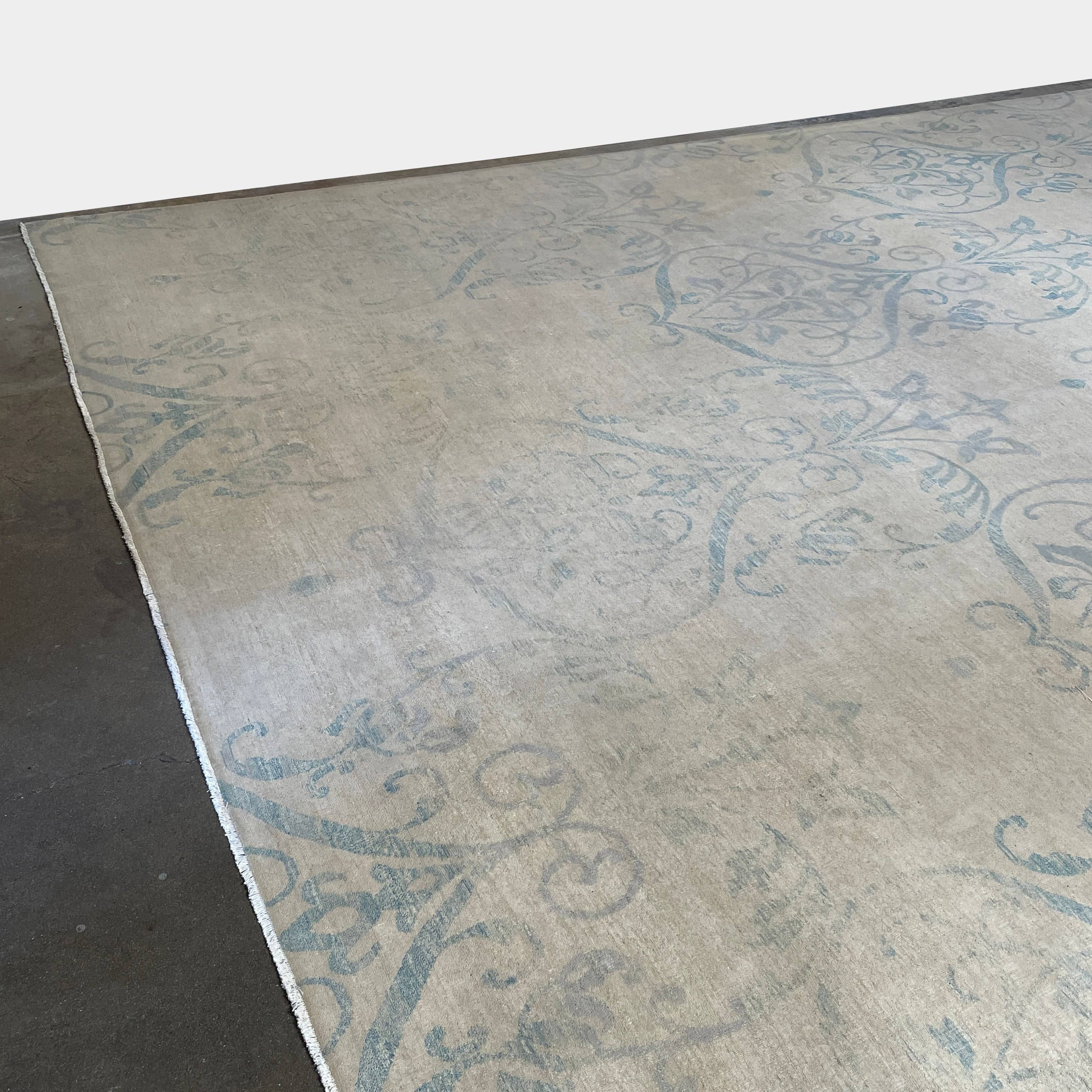 Close-up of a corner of an ornate, traditional Vintage rug with blue patterns on a beige background.