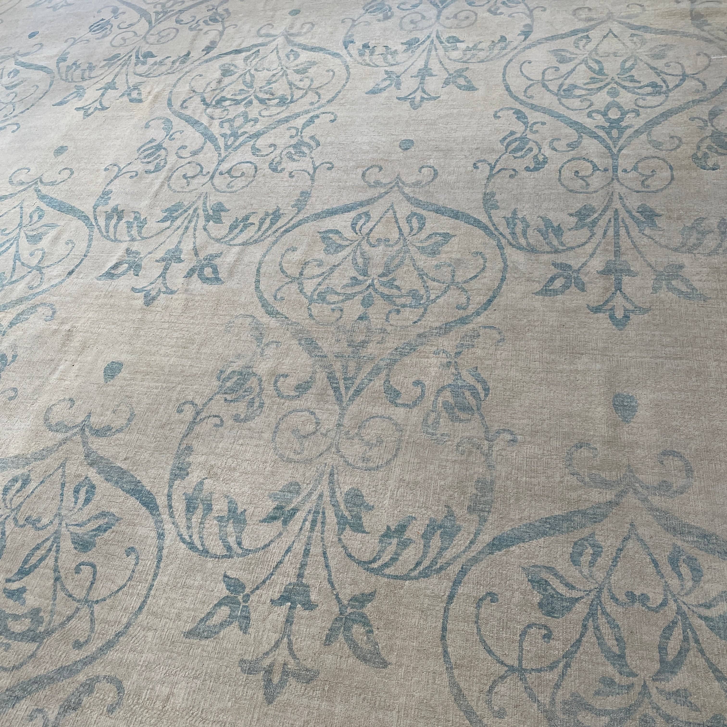 Close-up of a corner of an ornate, traditional Vintage rug with blue patterns on a beige background.