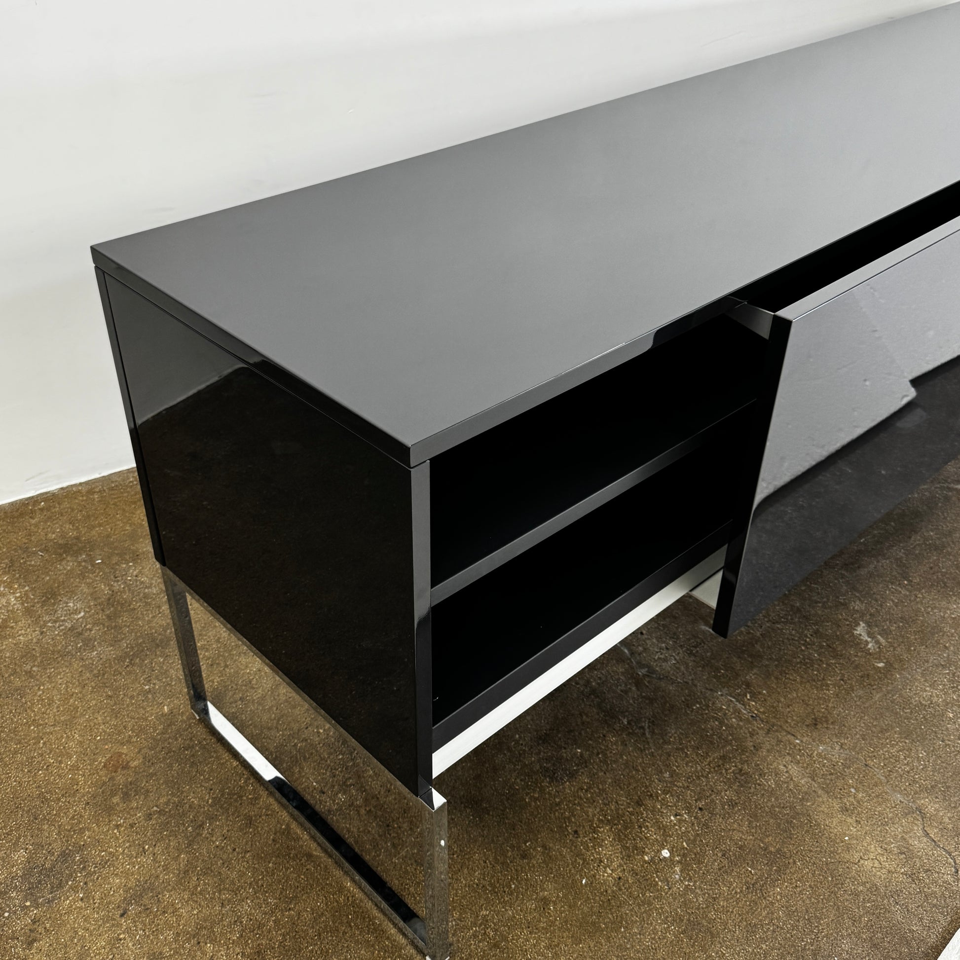 The B&B Italia Athos Console features a modern black rectangular design with a glossy finish and metal legs, showcased against a plain white background.