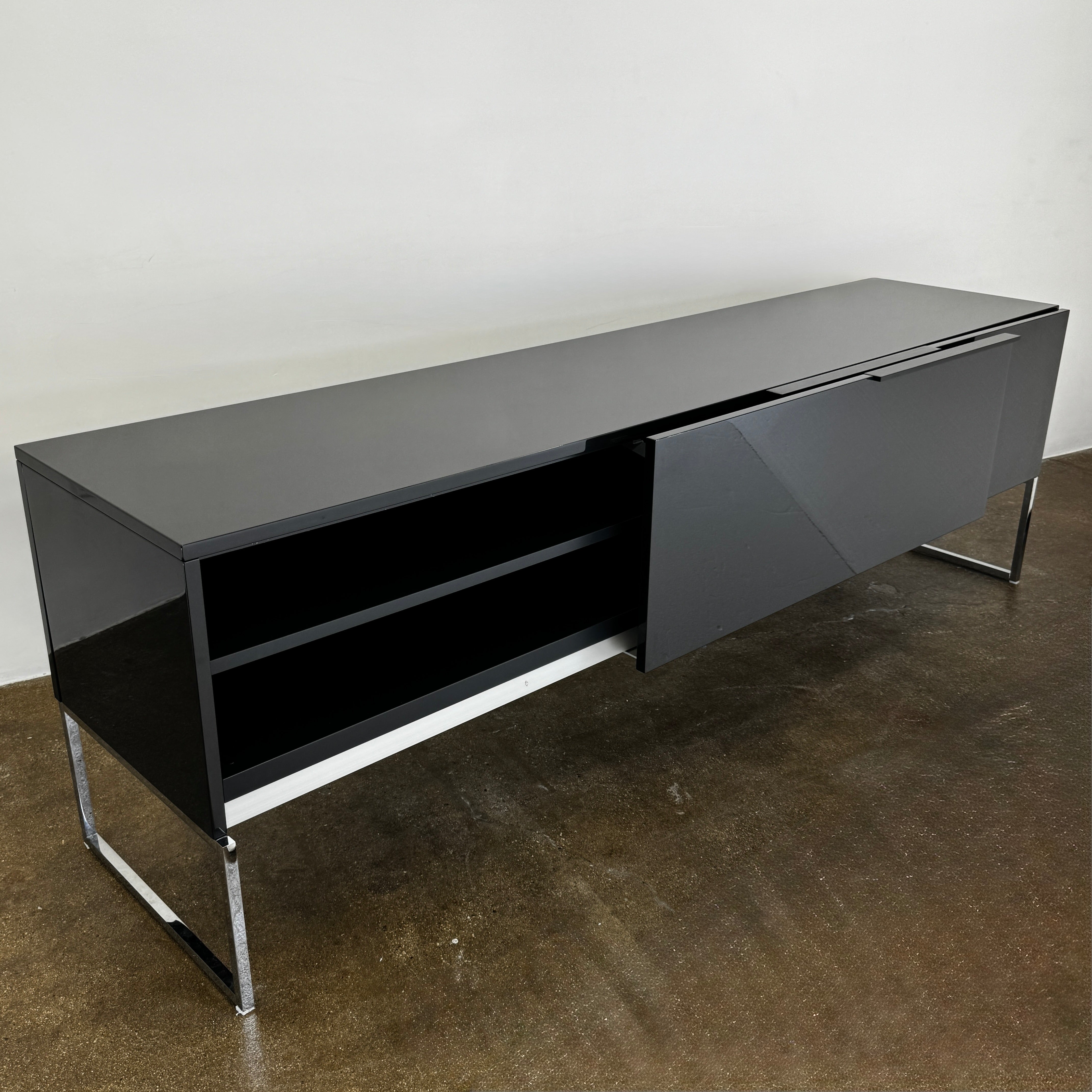 The B&B Italia Athos Console features a modern black rectangular design with a glossy finish and metal legs, showcased against a plain white background.
