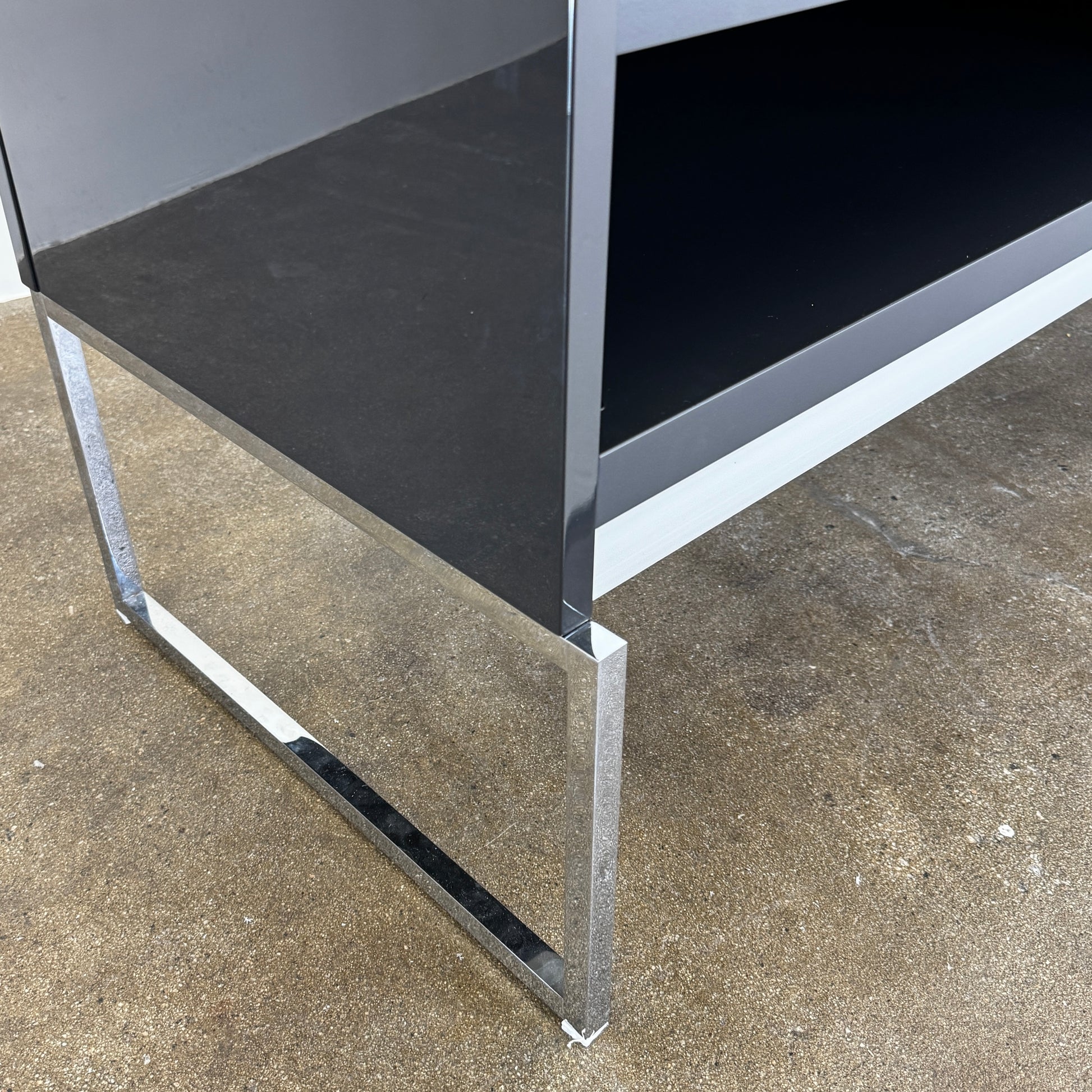 The B&B Italia Athos Console features a modern black rectangular design with a glossy finish and metal legs, showcased against a plain white background.