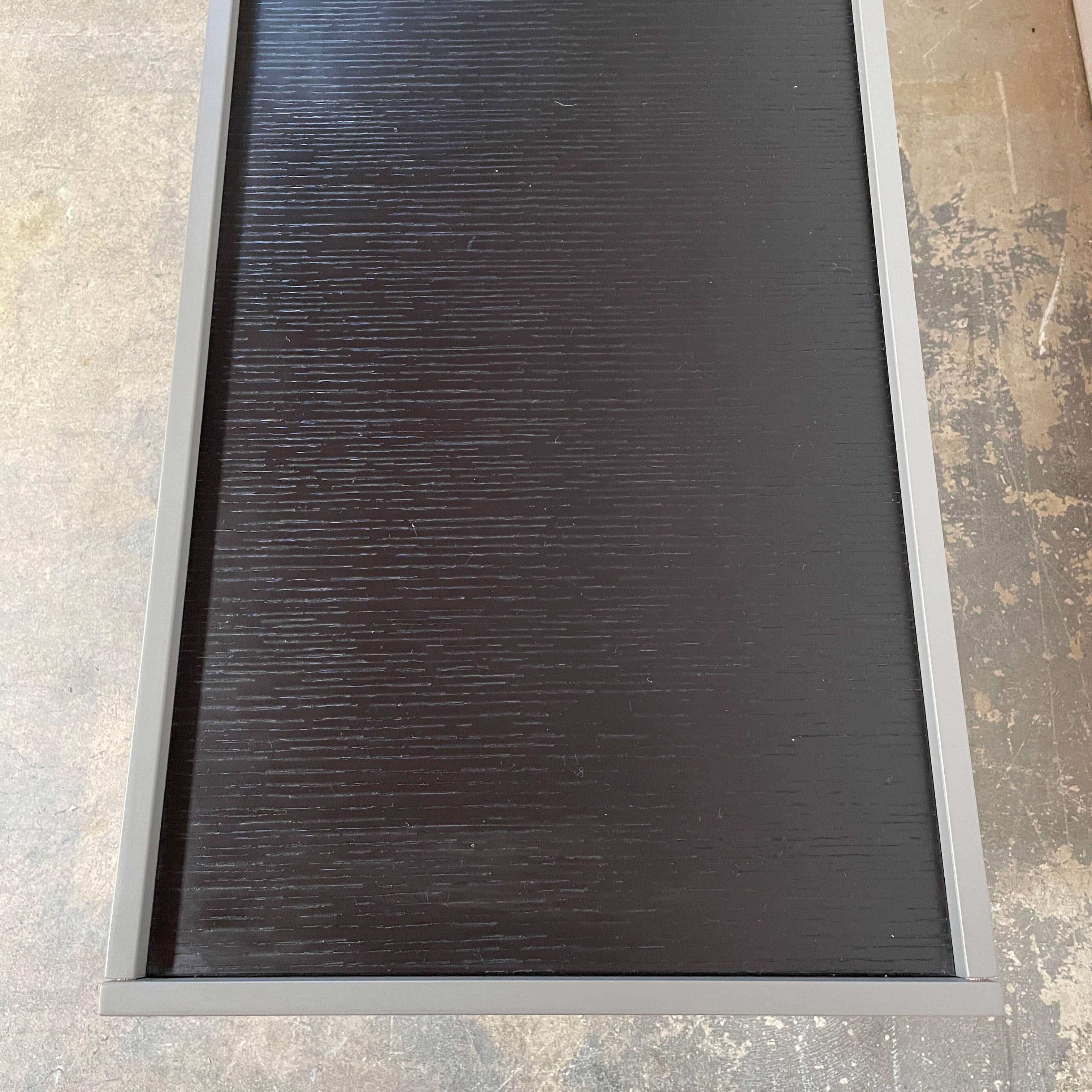 A Minotti Close Console with black legs and a glass top.