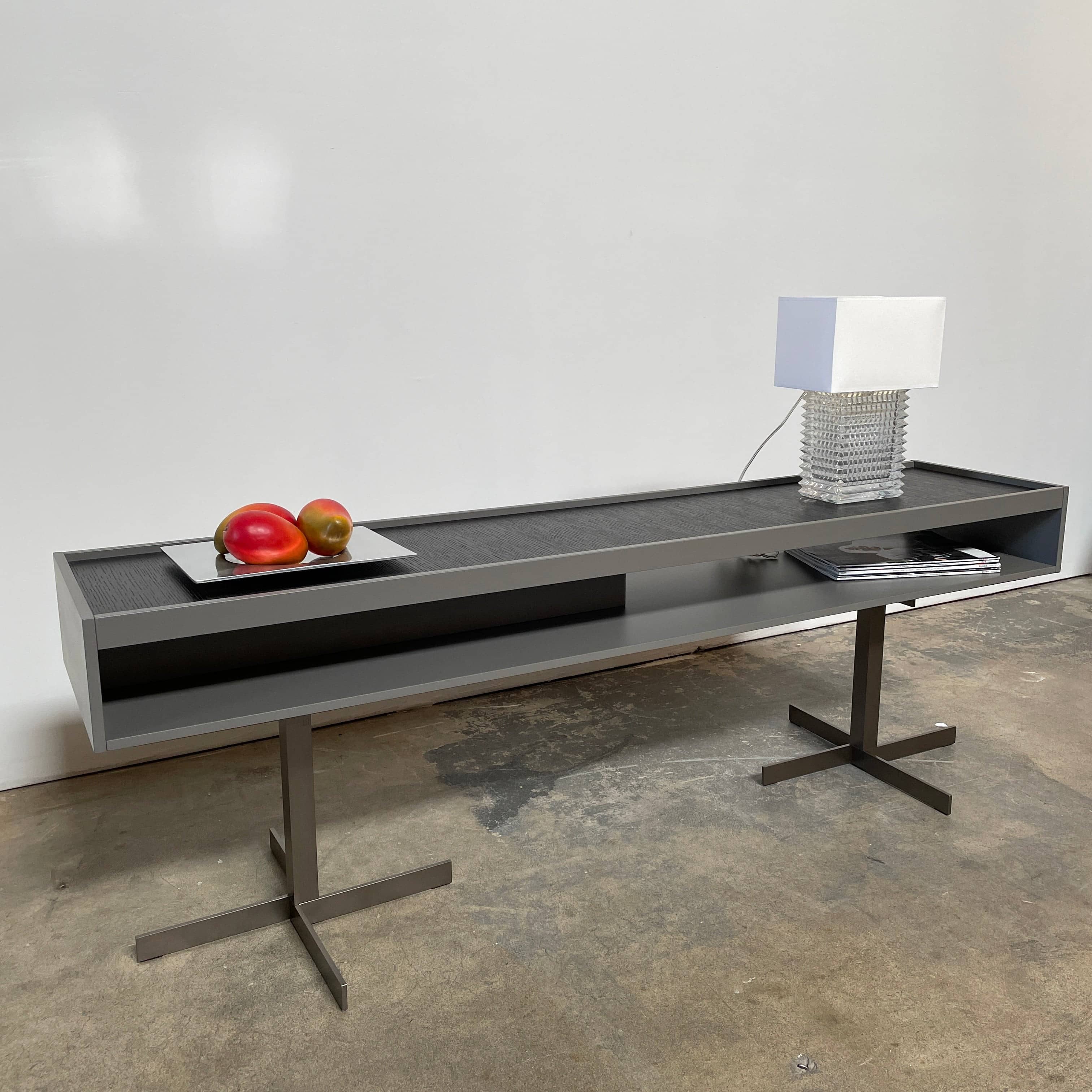 A Minotti Close Console with black legs and a glass top.