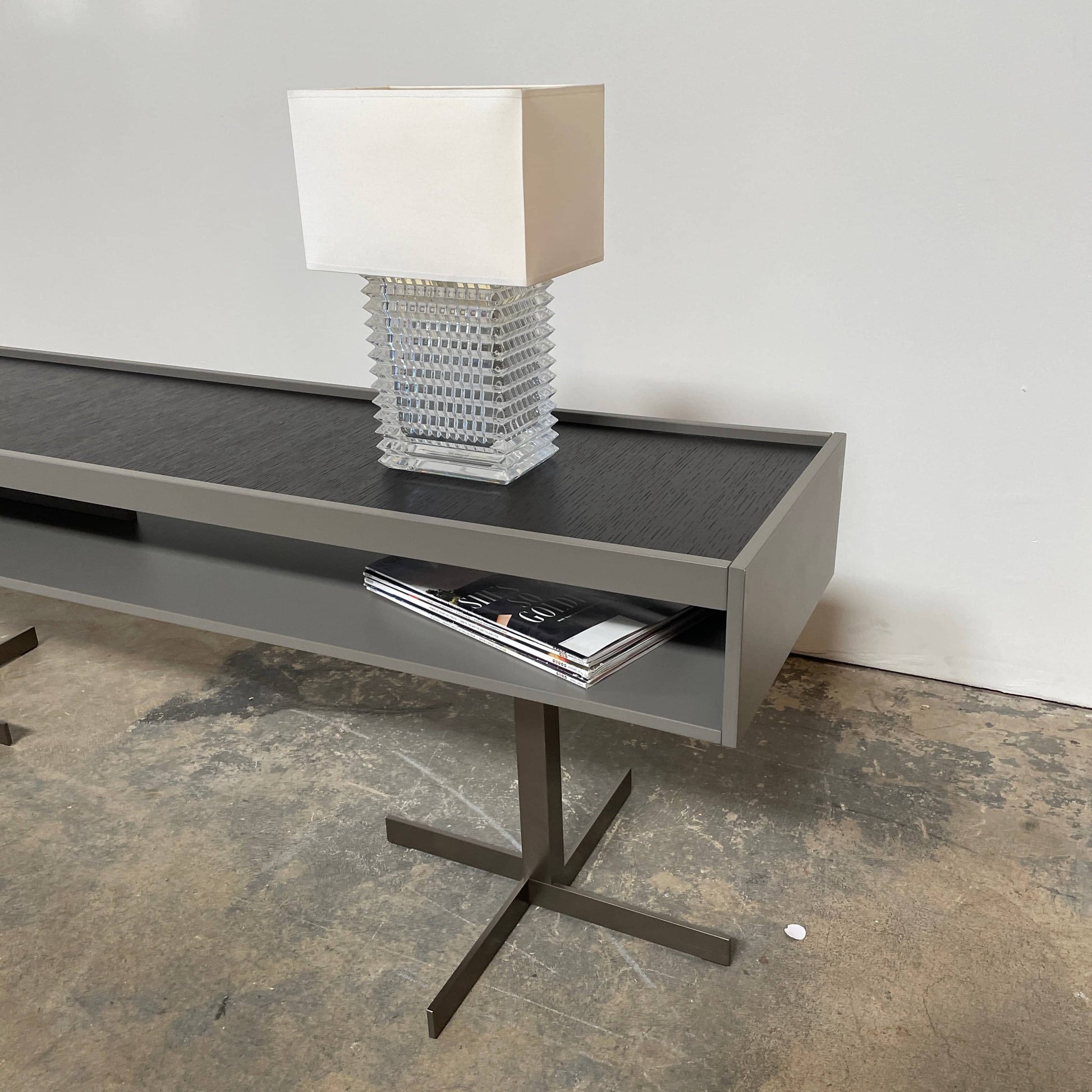 A Minotti Close Console with black legs and a glass top.