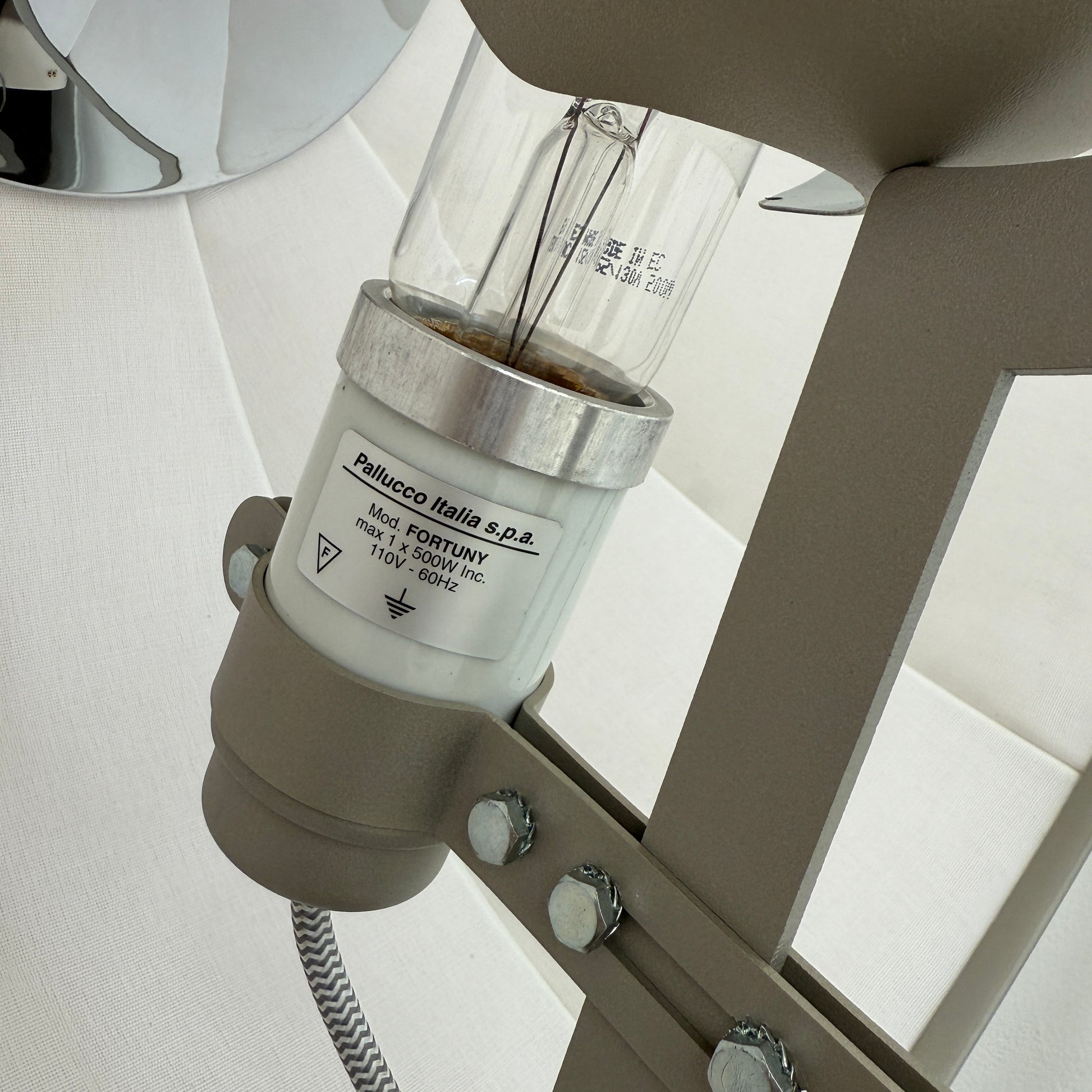 The Pallucco Italia Fortuny Ornament Floor Lamp, with its visible bulb and patterned spherical shade, gracefully stands on a plain white background, epitomizing the elegance of Pallucco Italia.